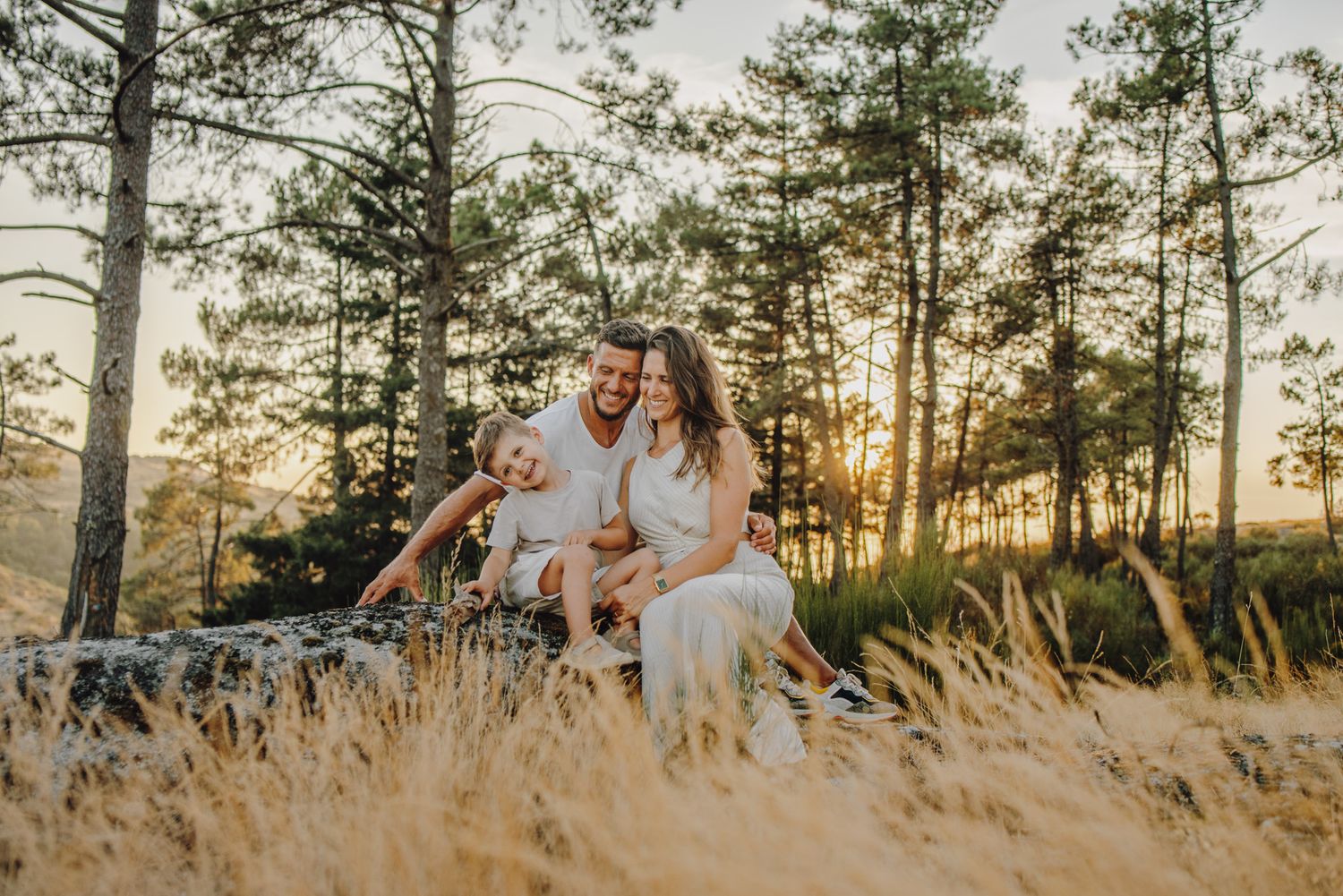 Panoramic view of family photoshoot in golden hour with pine forest backdrop.