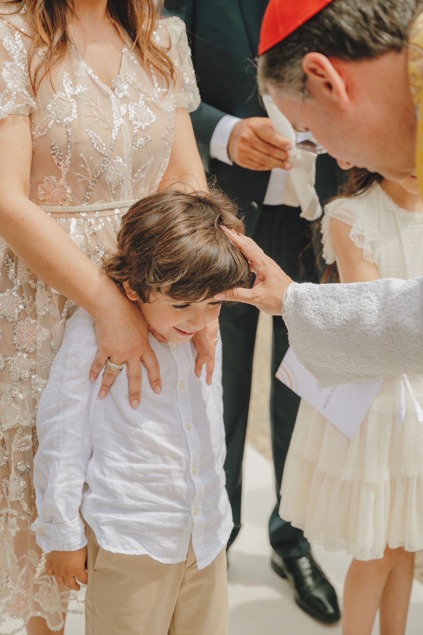 Children in white formal attire gather together at a special occasion.