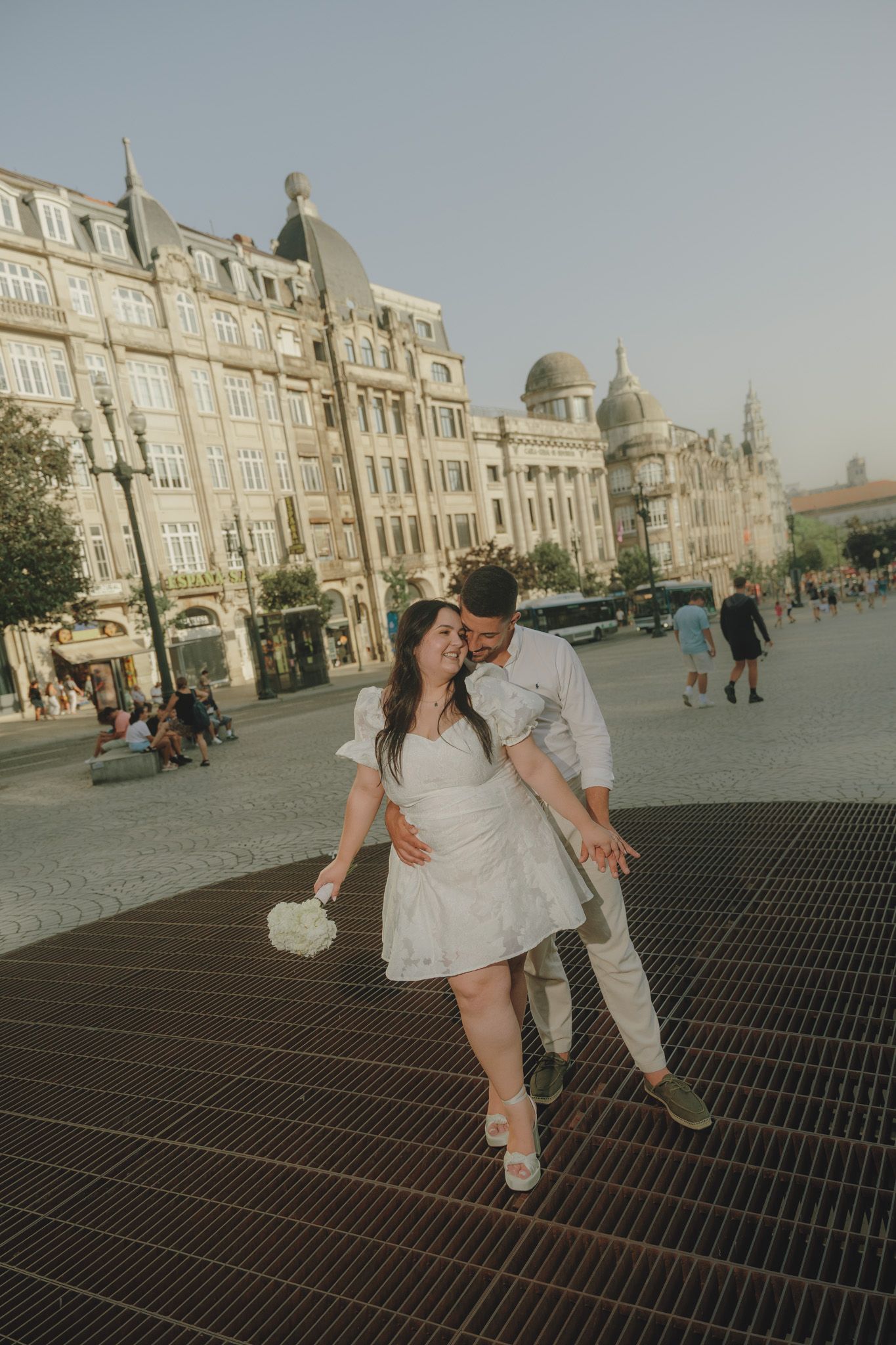 A couple sharing an intimate dance pose on a cobblestone plaza with historic buildings in the background.