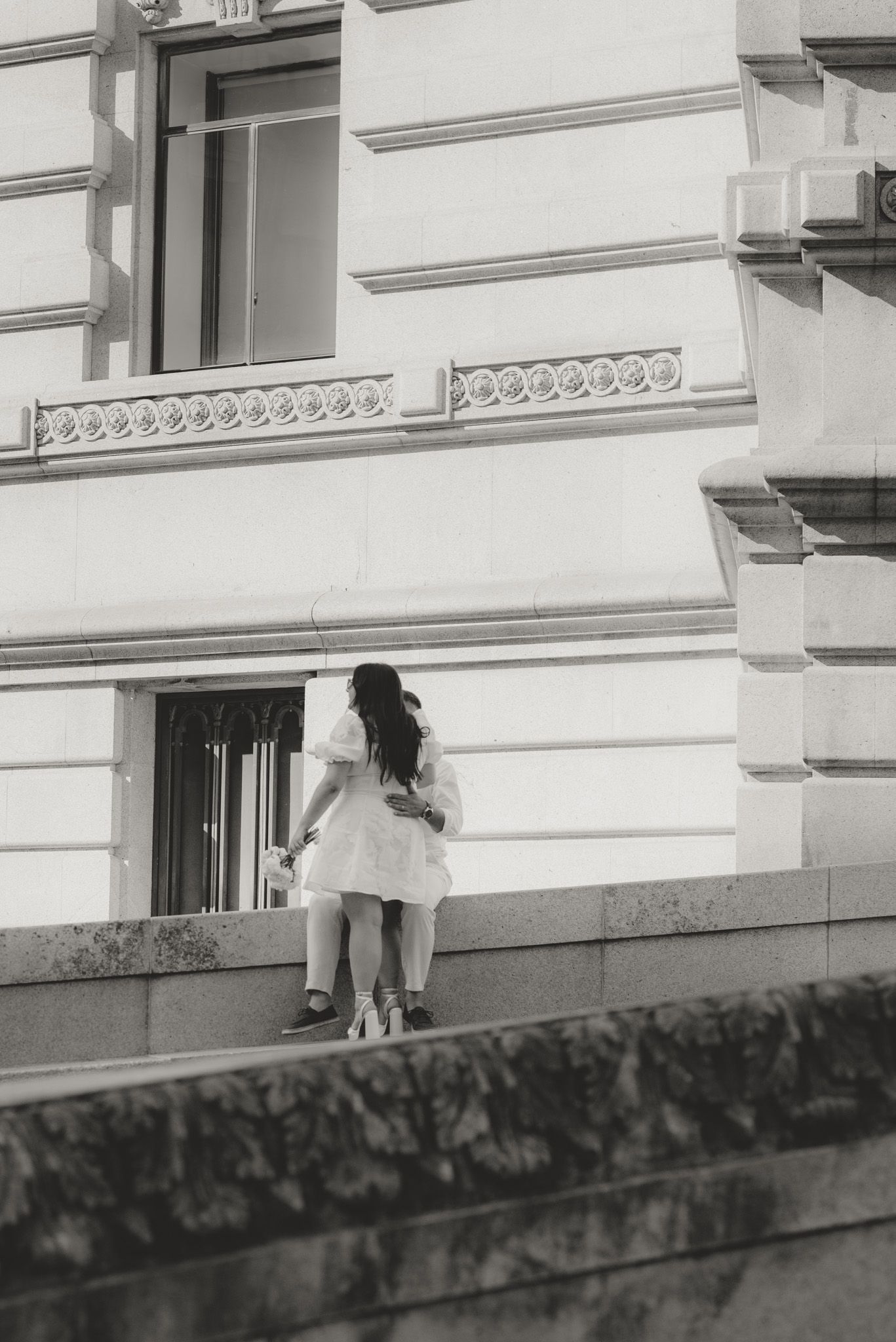 A sequence of images showing two people sitting against a white building exterior.