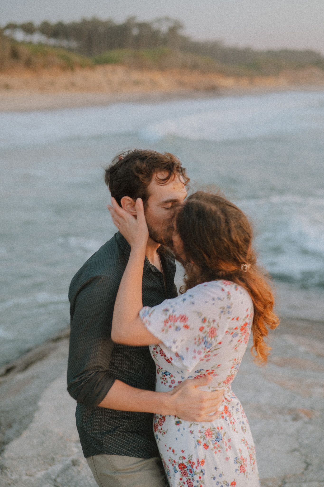 Romantic seaside moment captured on rocky beach cliffs during golden hour.