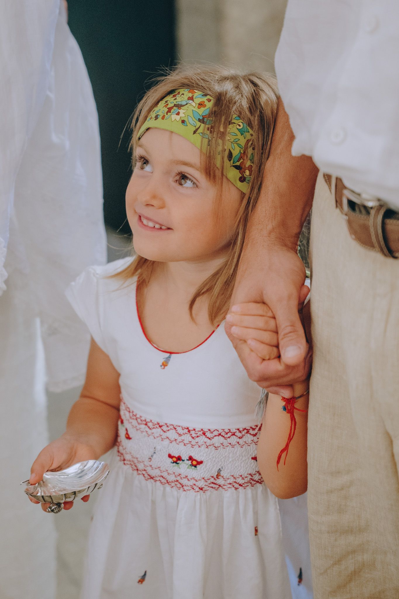 Young person in white dress with embroidered details and floral headband.