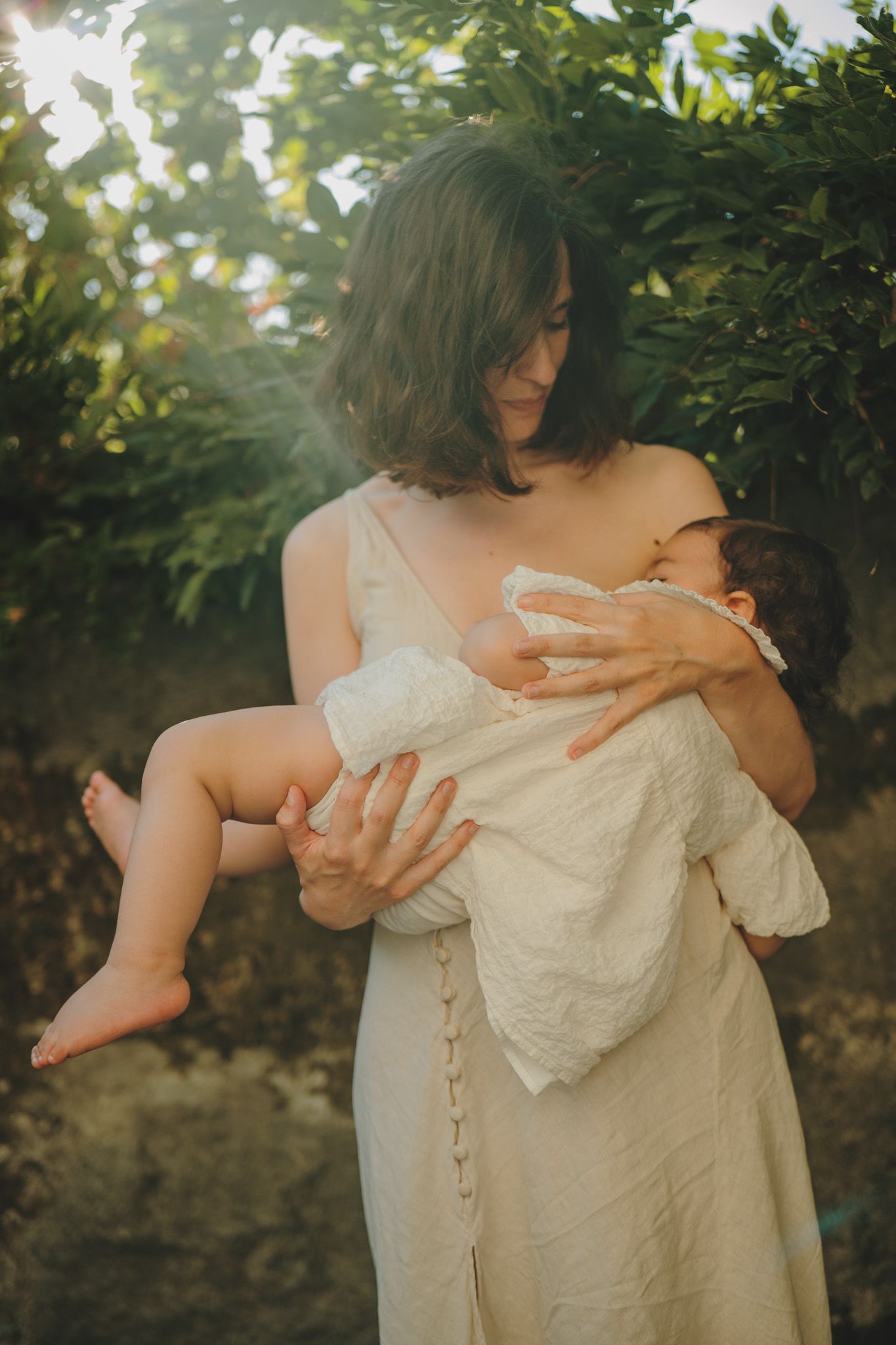 Intimate family moment captured in soft natural lighting against garden backdrop.