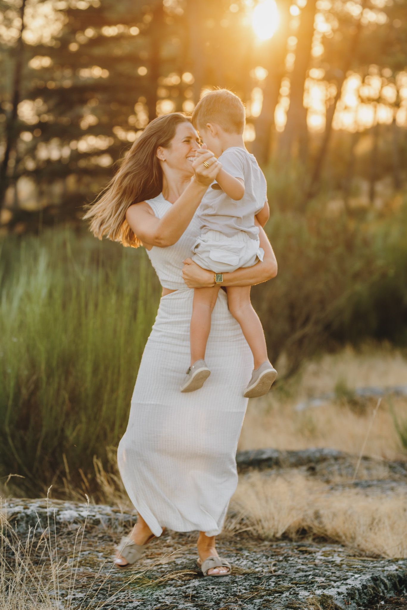 Playful family moments captured in warm sunset light among tall grass.
