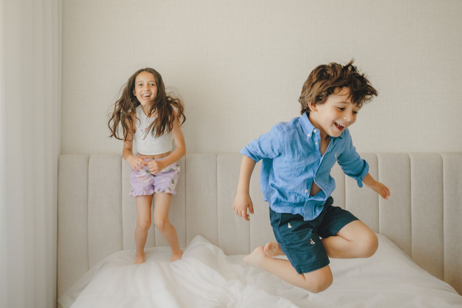 A series of playful lifestyle photos showing someone jumping and posing on a light gray couch against a neutral wall.