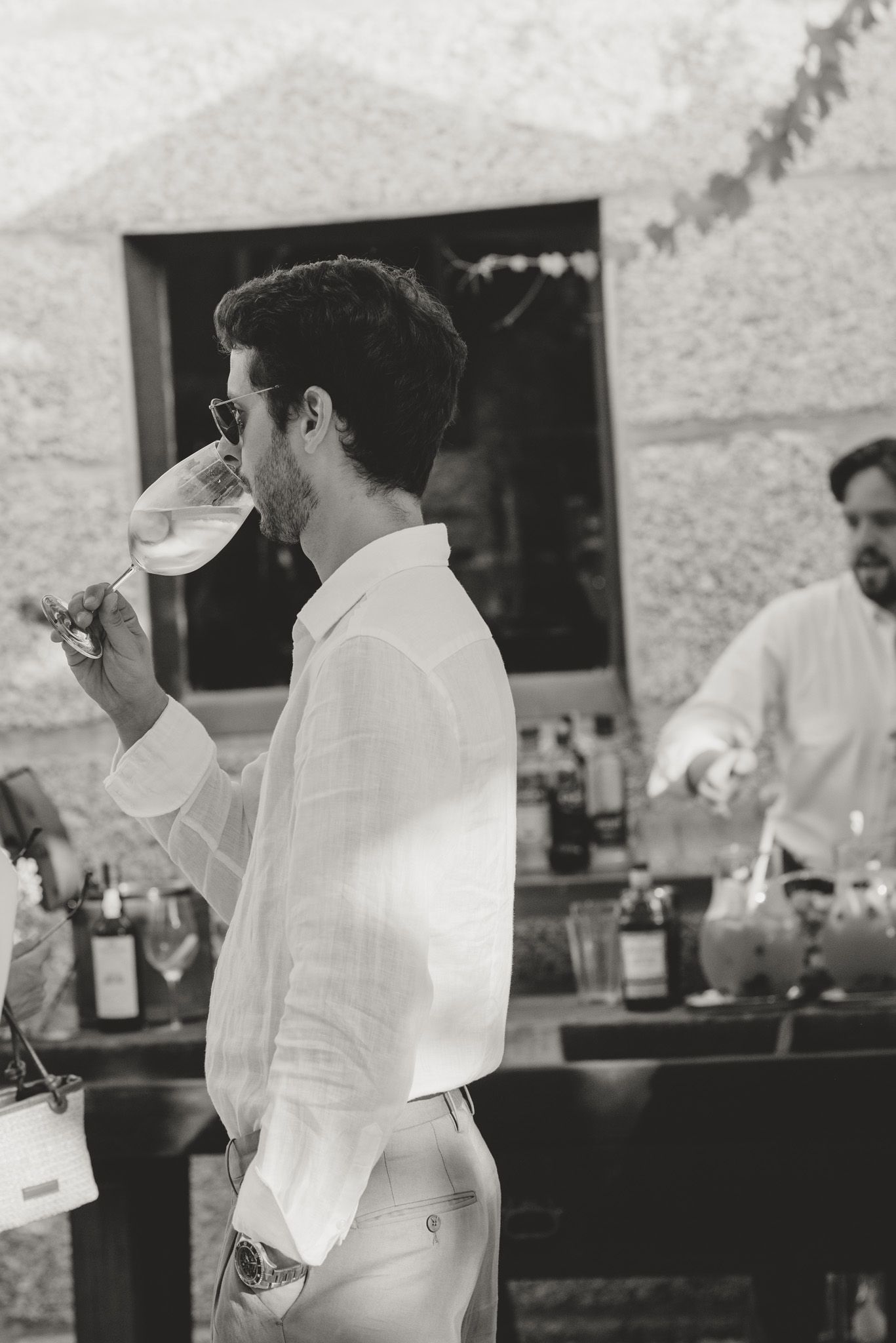 Staff in crisp white uniforms preparing drinks at an outdoor bar counter.