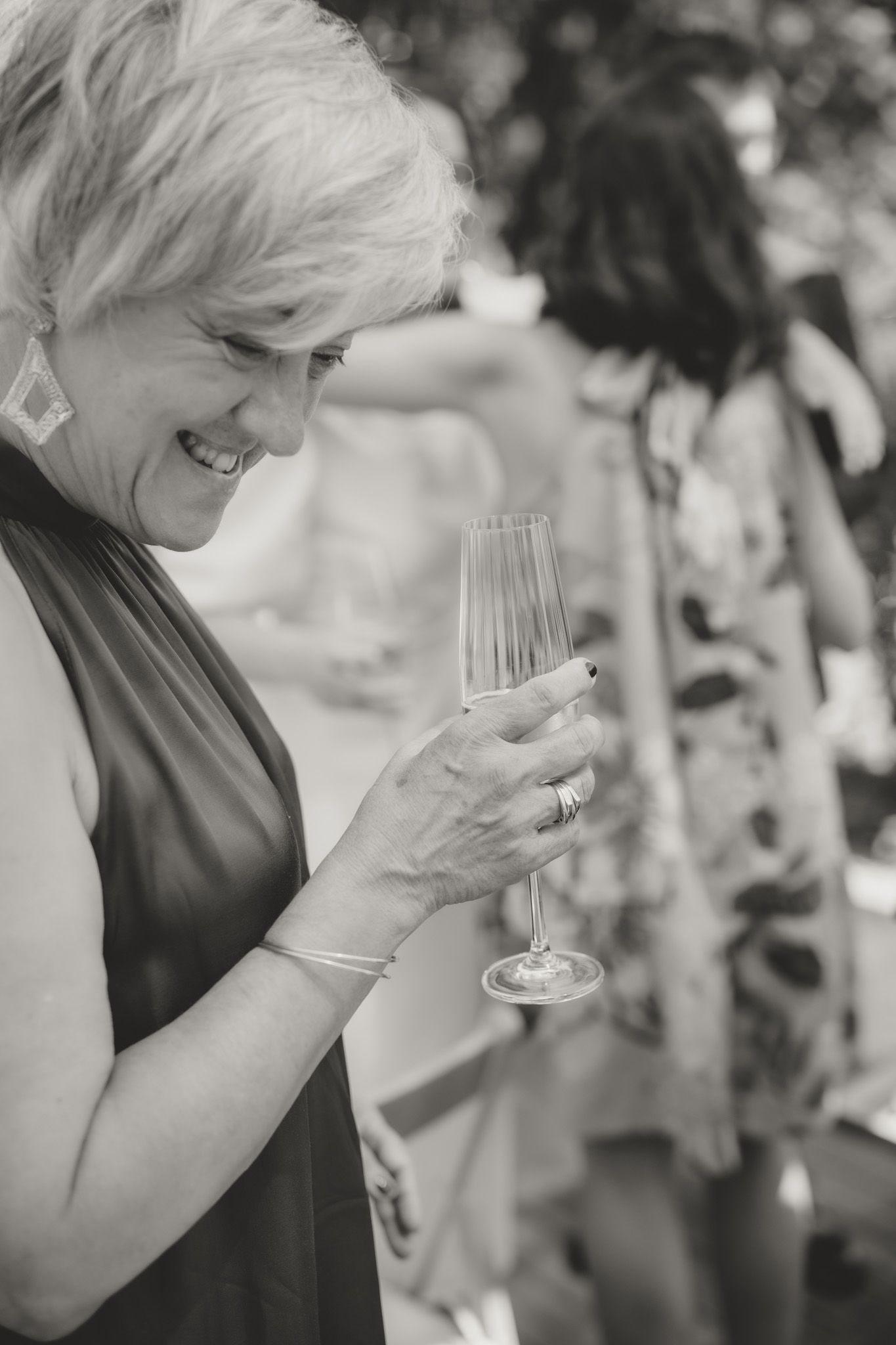 Wedding guests laughing and holding champagne glasses during celebration.