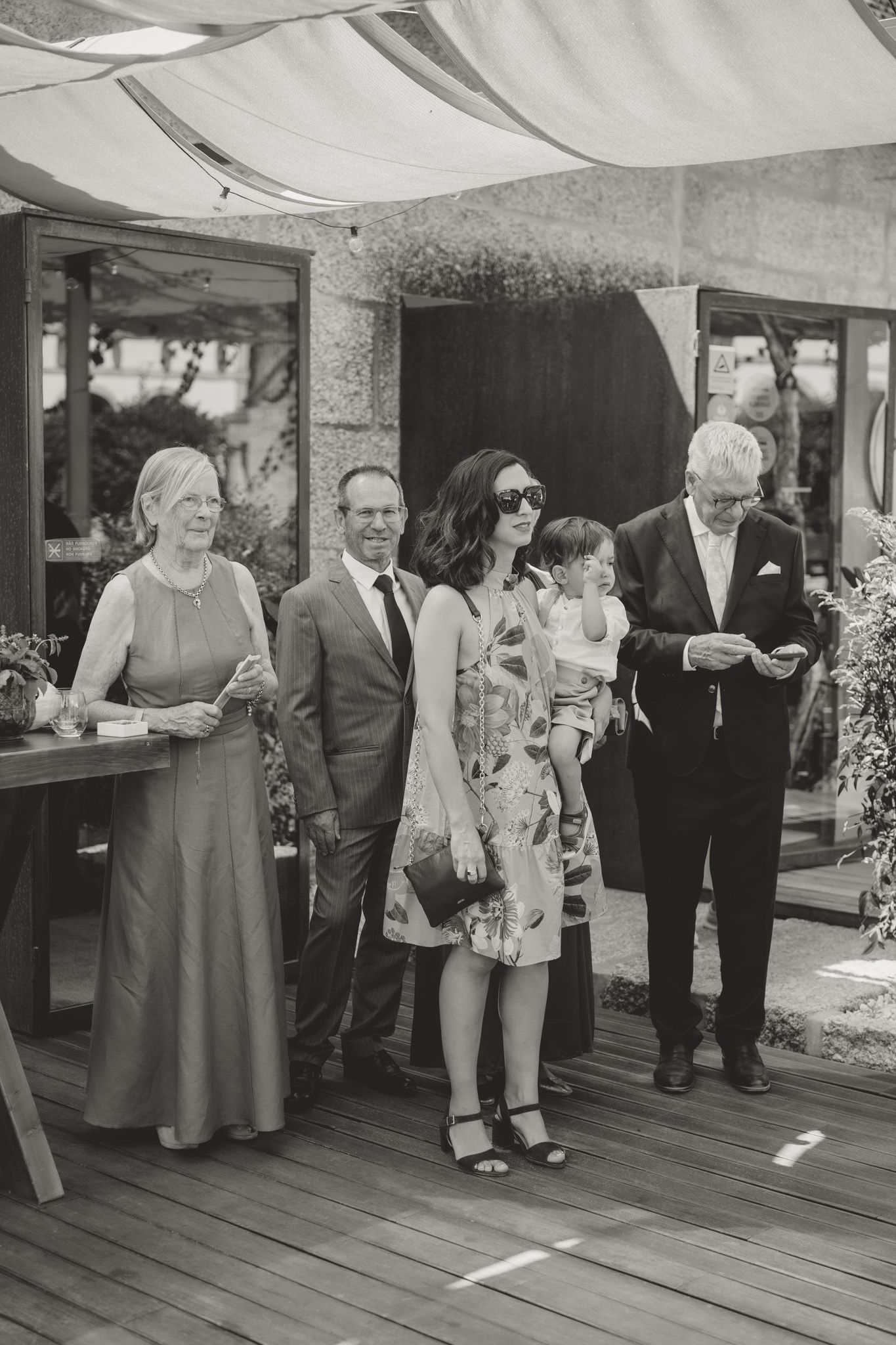 Wedding guests mingling on a covered deck during a reception celebration.