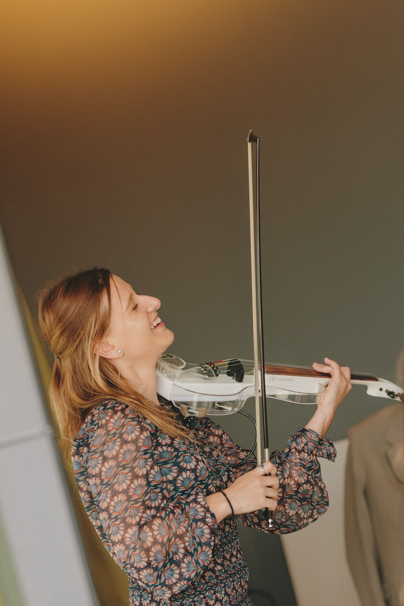 A musician performs on an electric violin in a floral print dress.
