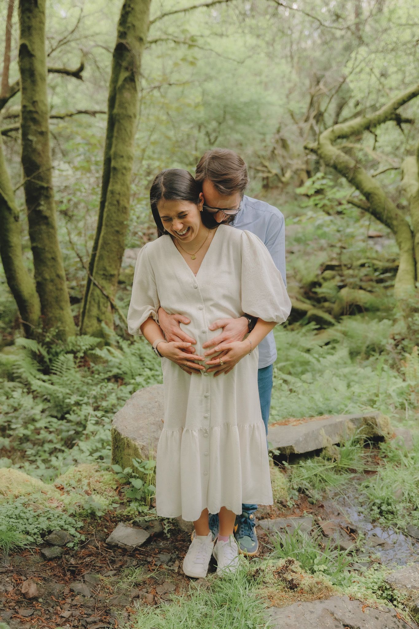 Couple sharing intimate moments in a lush green forest setting.