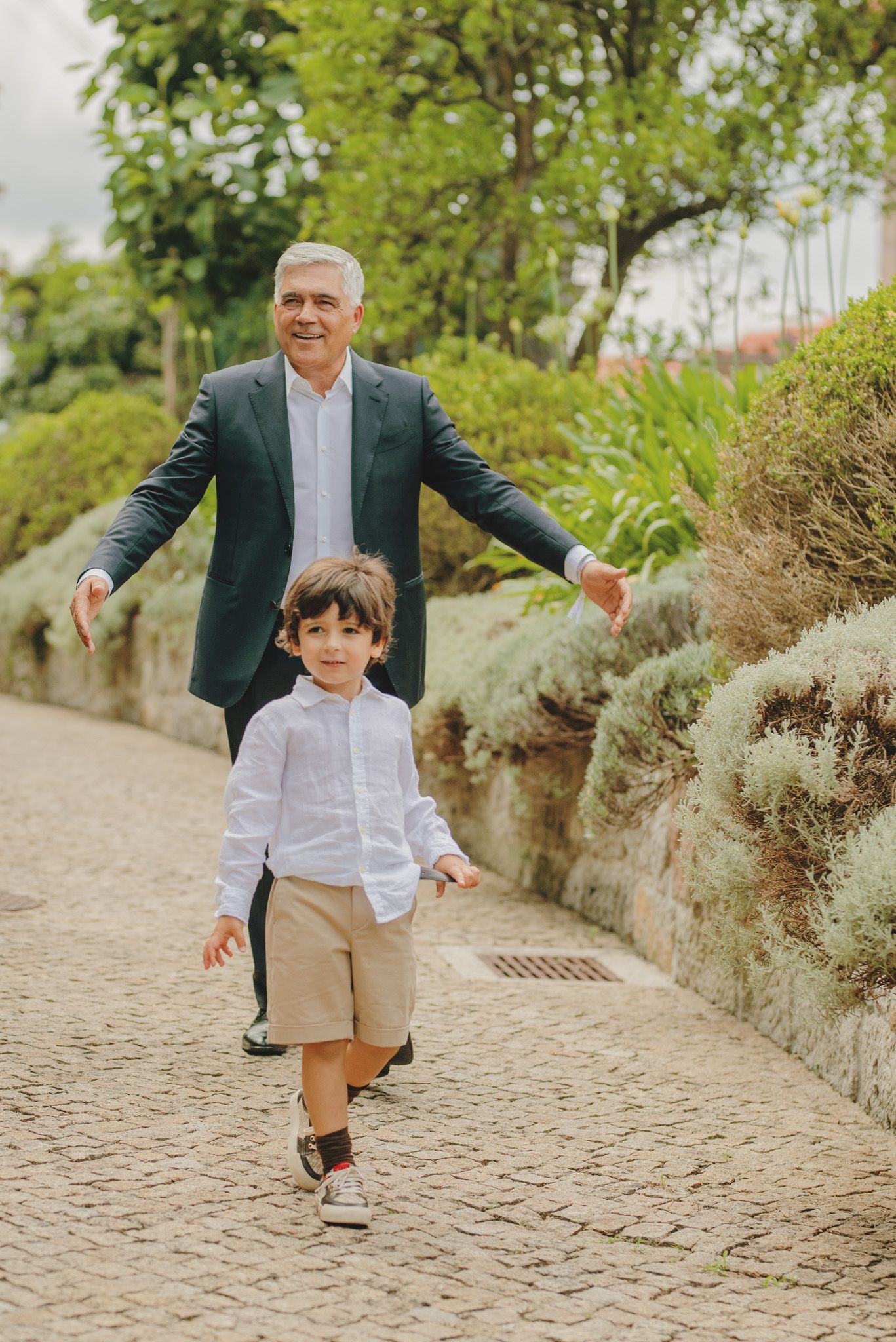 A series of playful walking shots on a cobblestone path with a green garden backdrop.