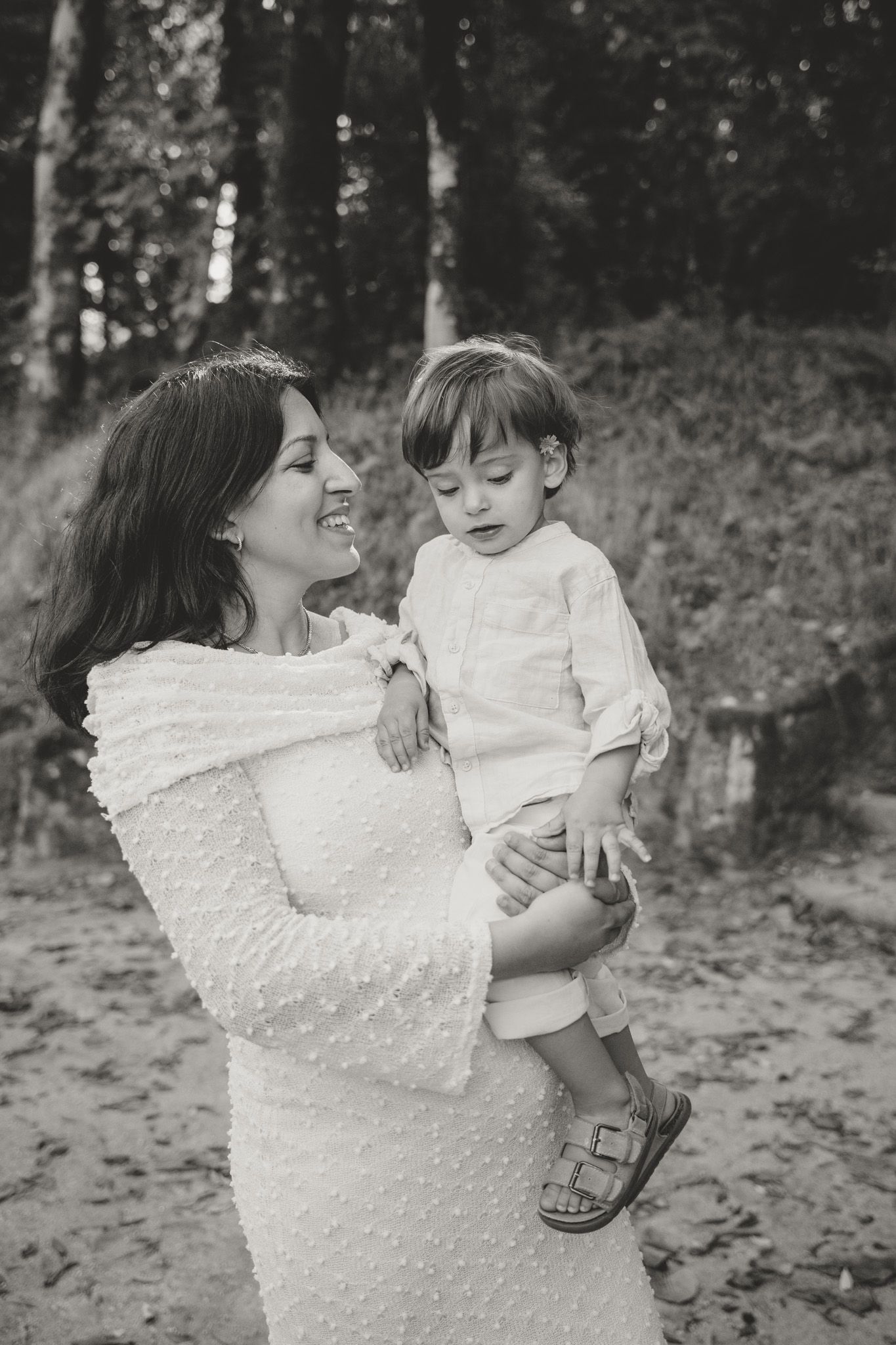 Black and white portrait of a parent and child sharing a loving moment outdoors.