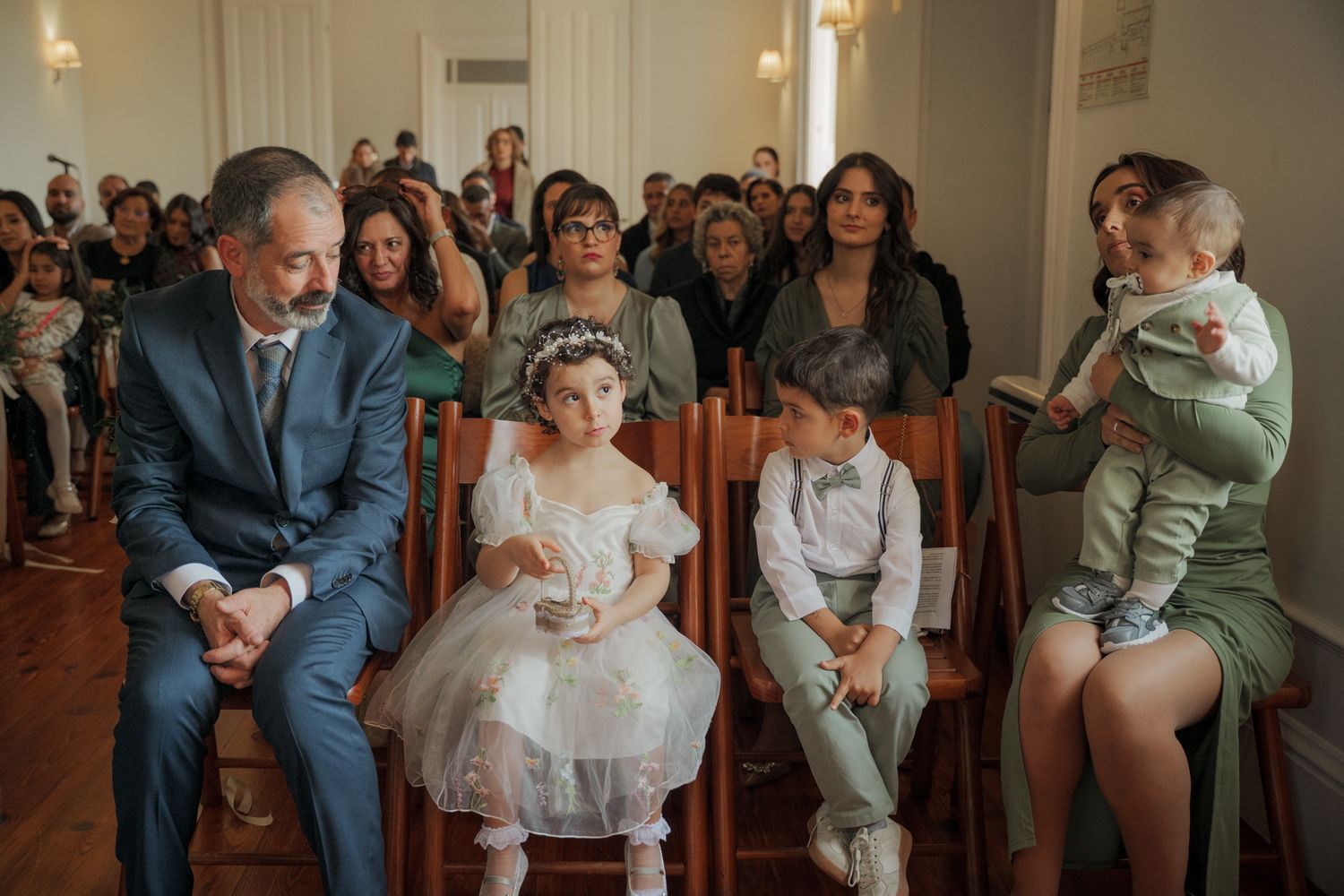 Wedding guests seated in rows during an indoor ceremony with warm lighting.