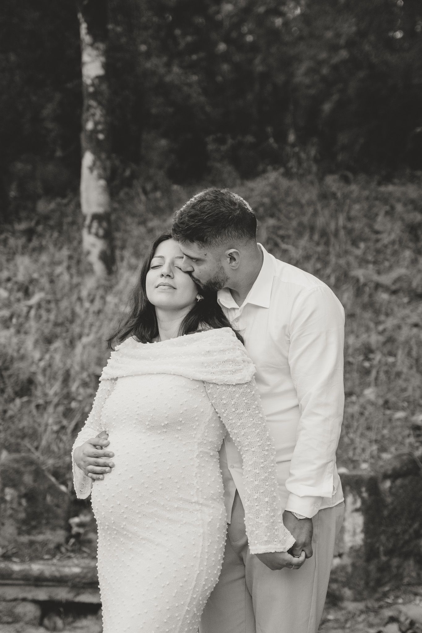 A romantic black and white maternity photo showing an intimate moment between partners.