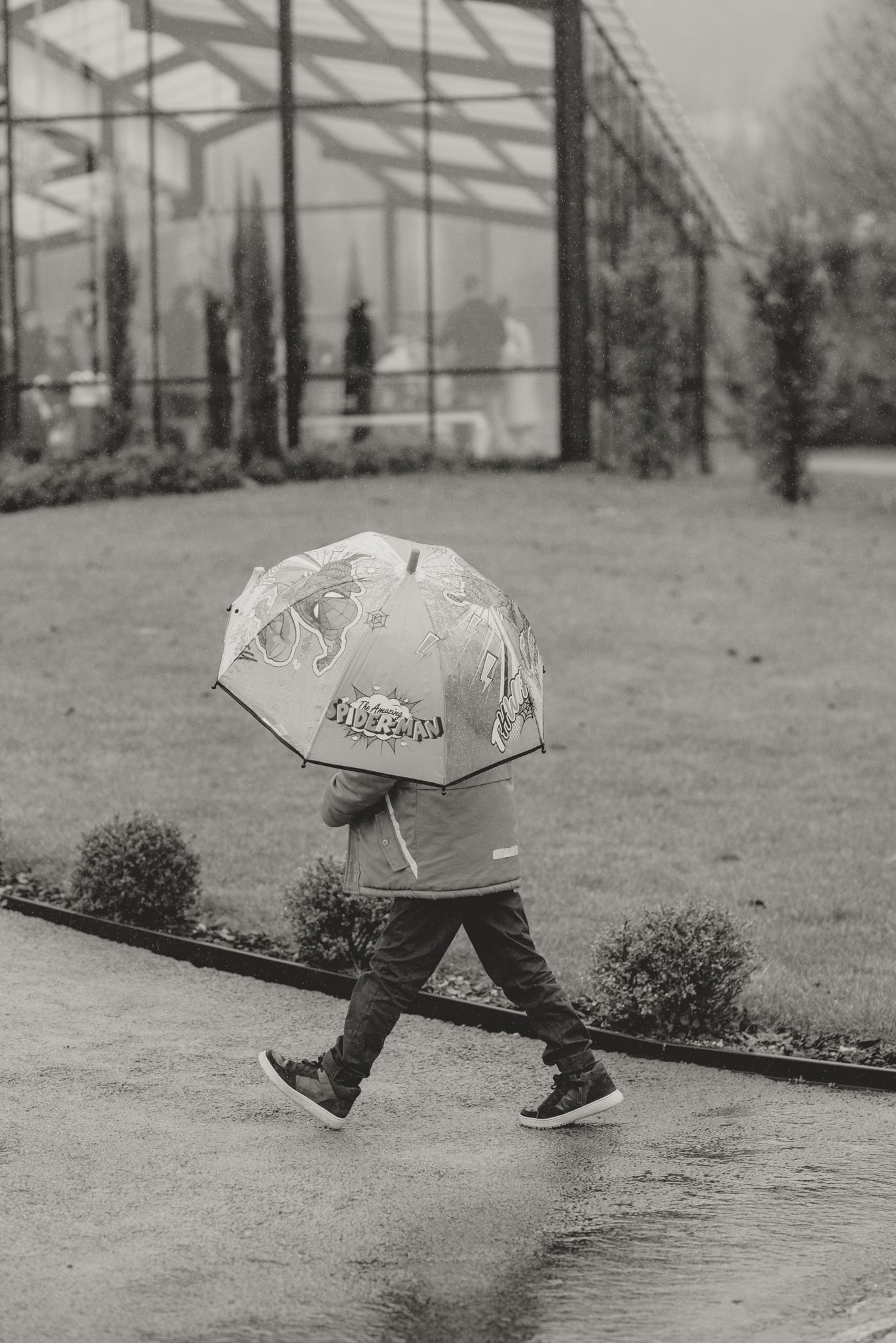 Close-up of feet walking with an umbrella in rainy weather.