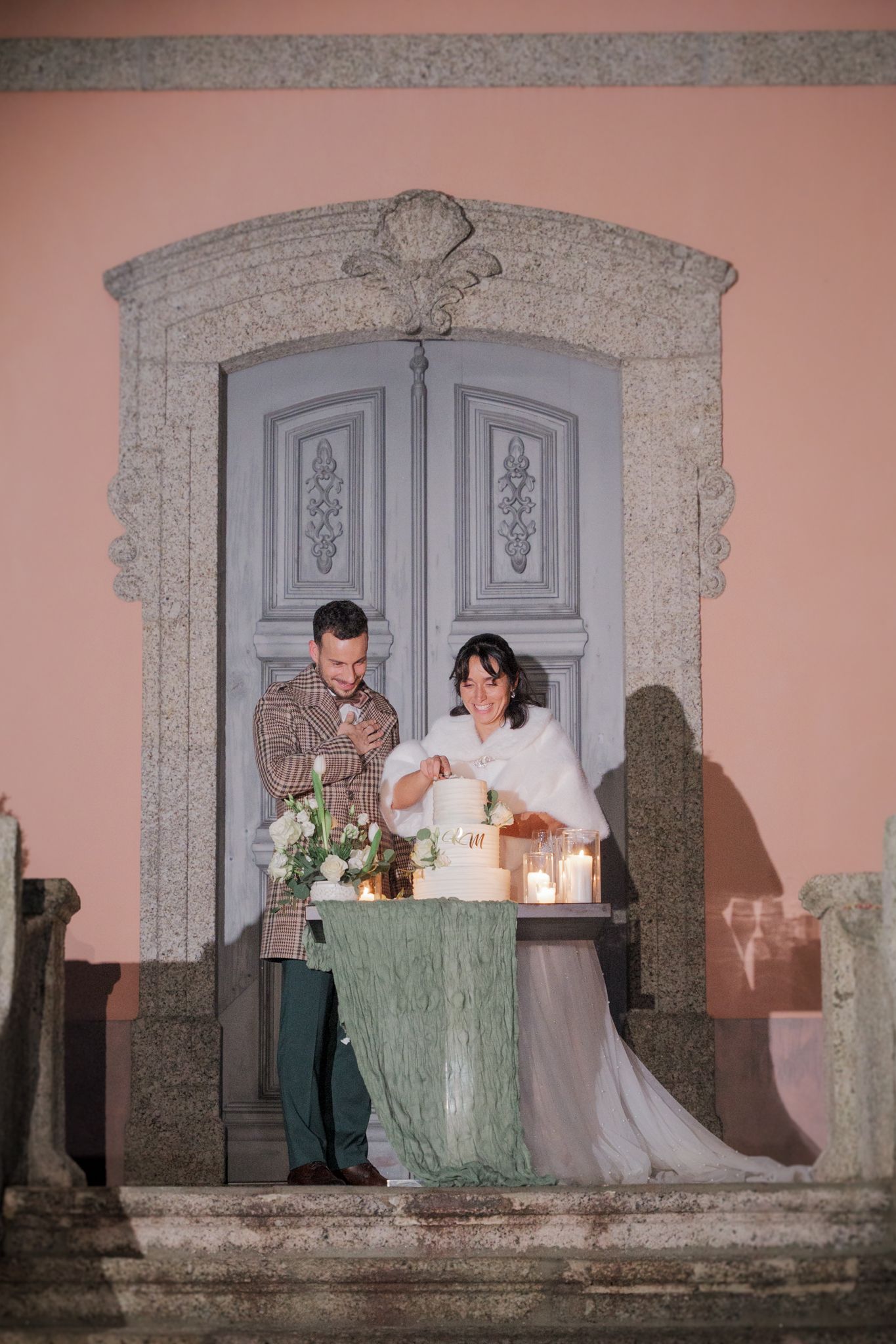 Wedding reception scene on a pink stone balcony with decorative grey doorways.