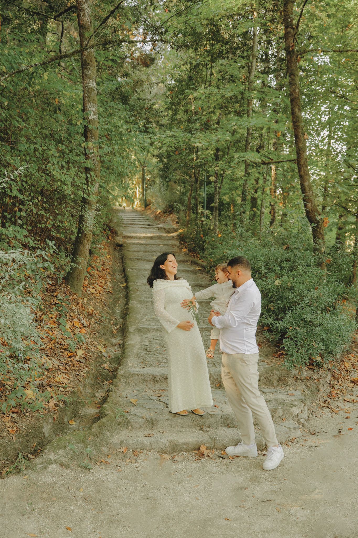 A couple shares an intimate moment on a wooded path during an autumn photoshoot.
