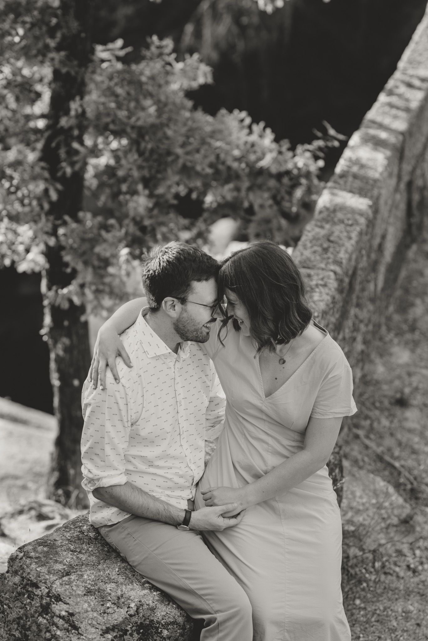 A tender moment captured in black and white as a couple sits together outdoors.