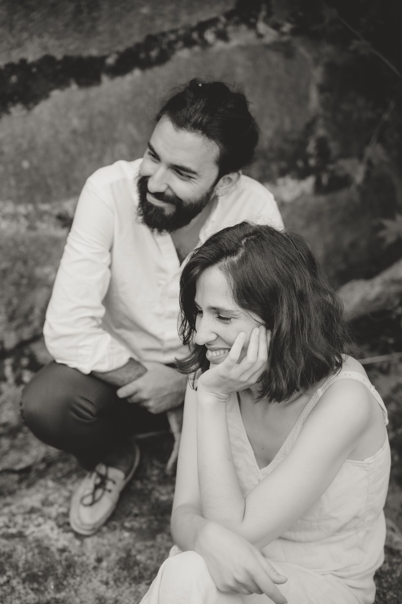 Black and white outdoor portrait capturing intimate moment between couple on grass.