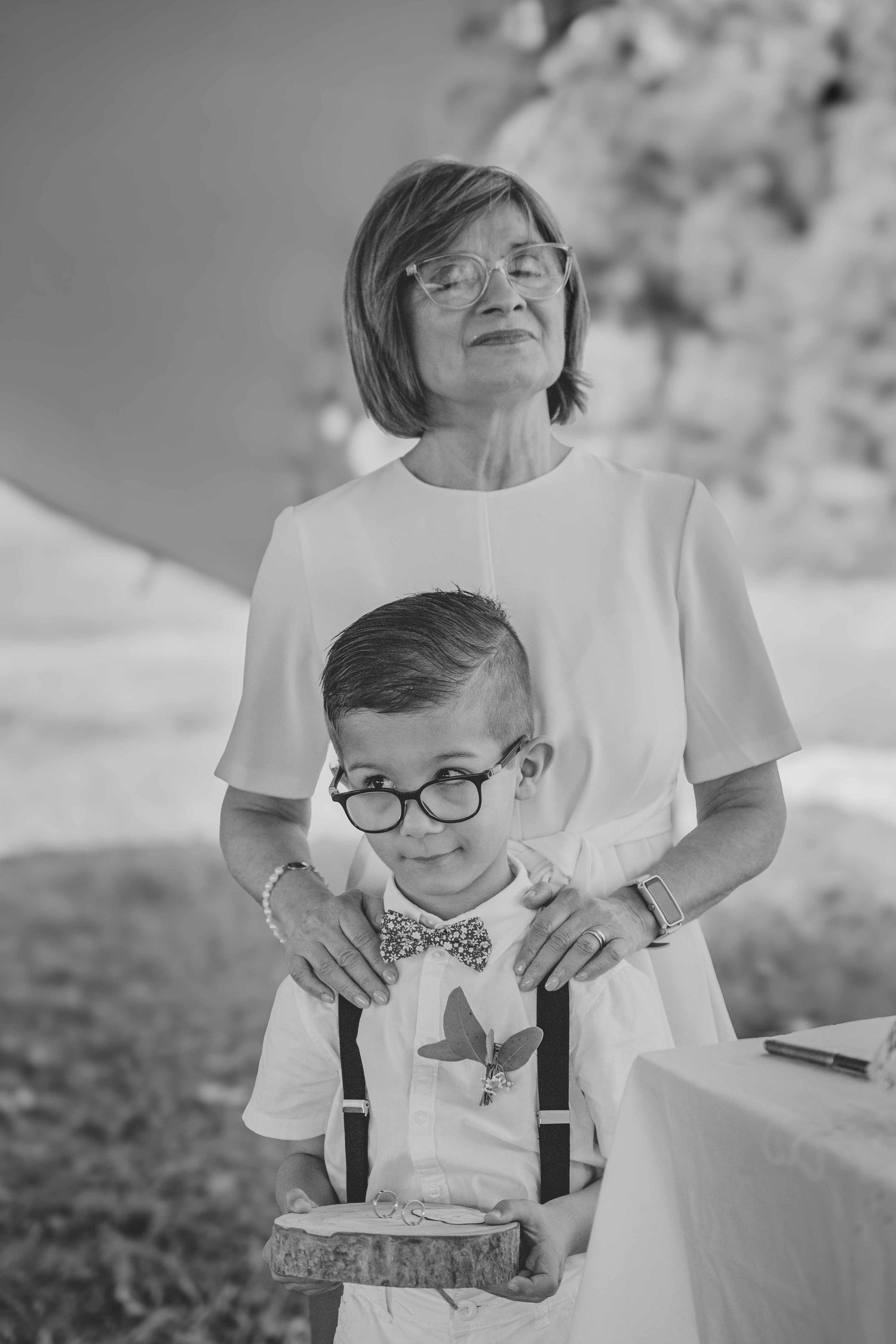 A series of black and white photos showing tender moments between a parent and child wearing white shirts outdoors.