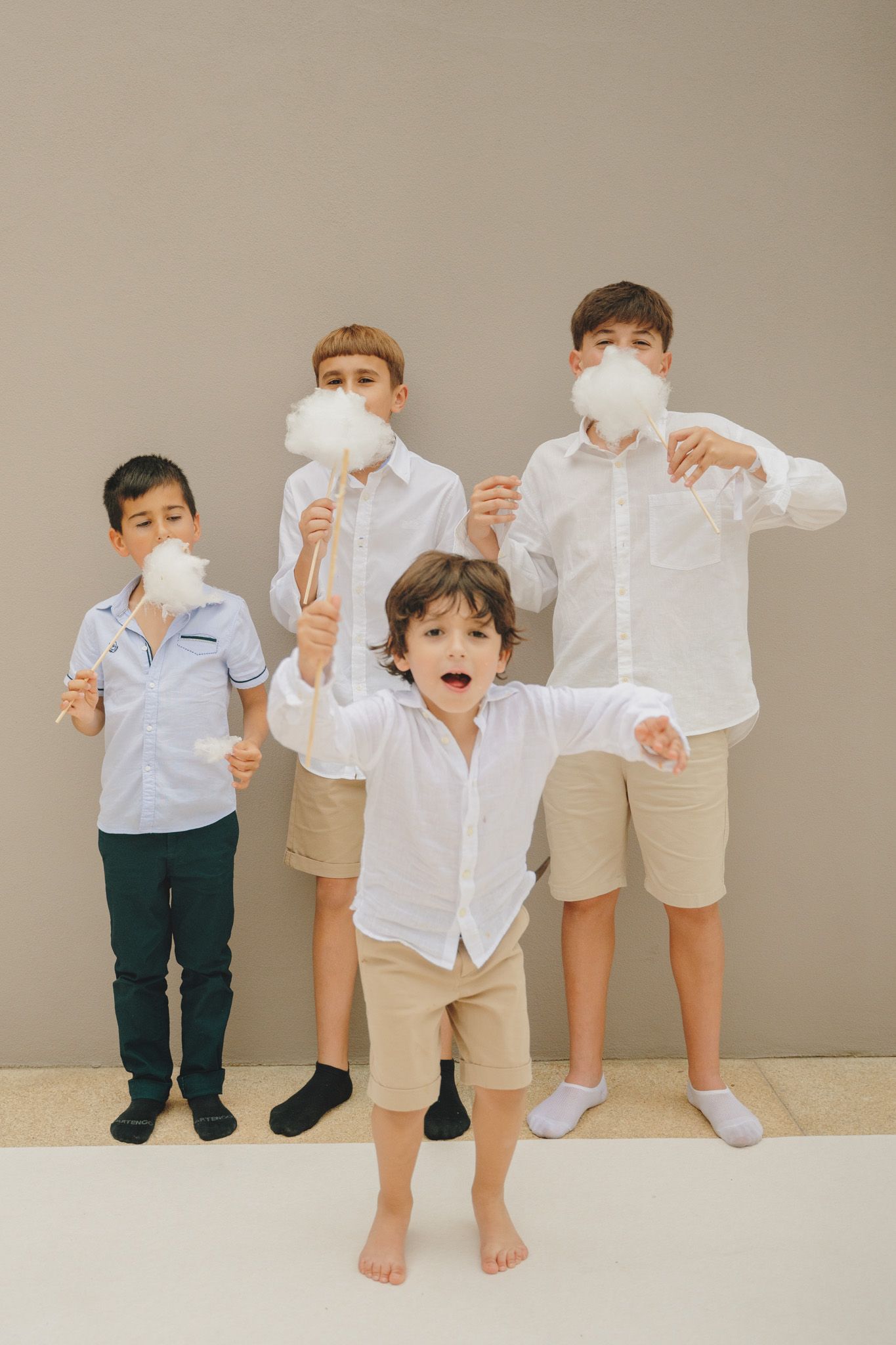 Children in coordinated white shirts and khaki shorts playing with cotton candy.