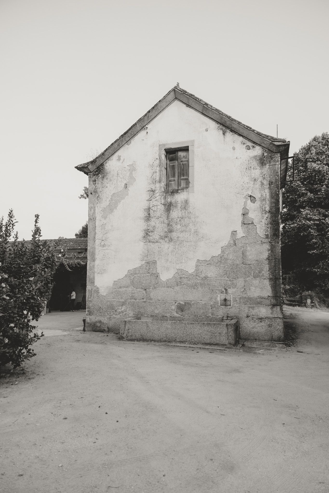 A weathered white building with damaged walls stands against a light background.