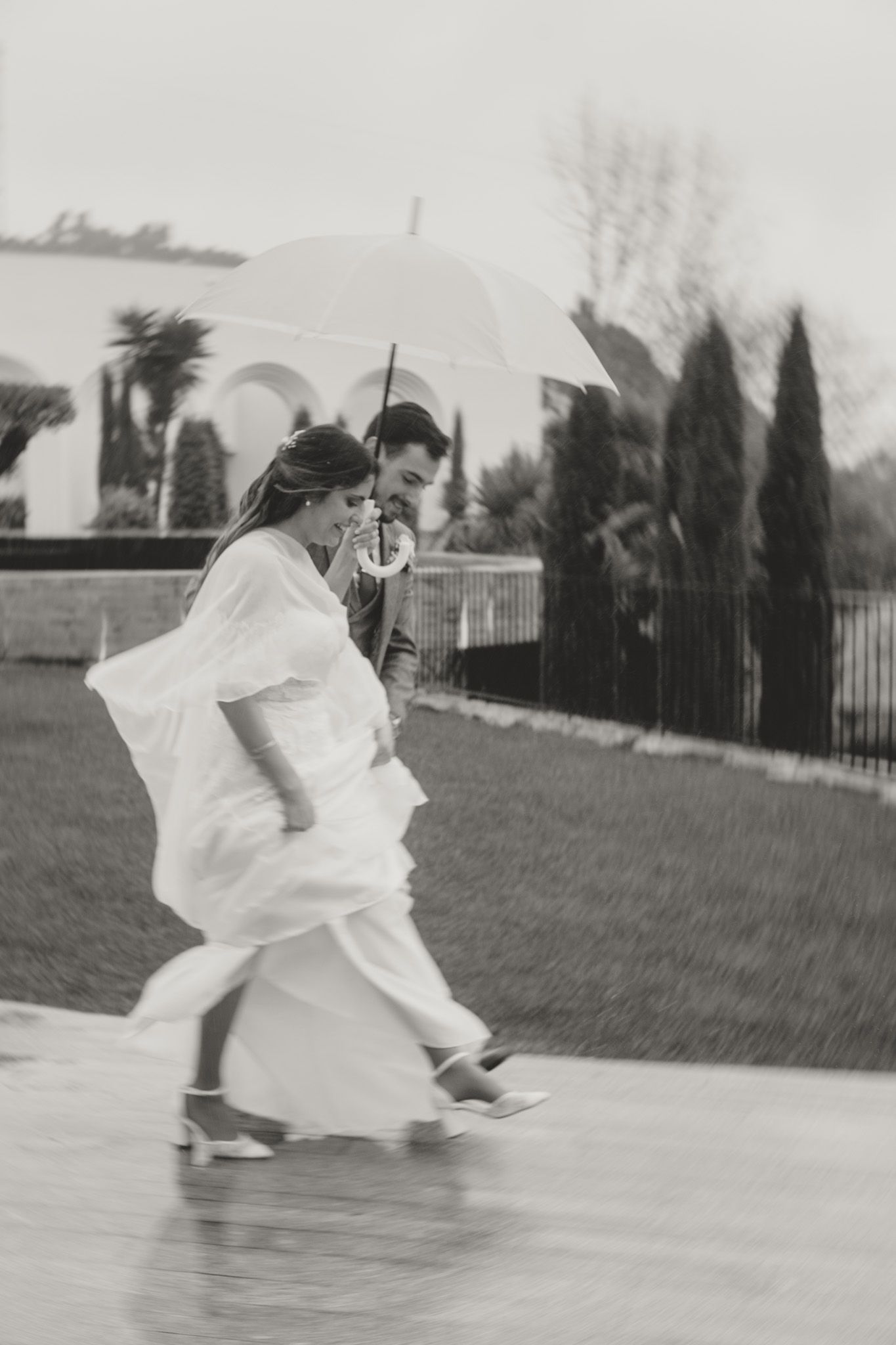 Flowing white wedding dress twirling in motion against outdoor backdrop.