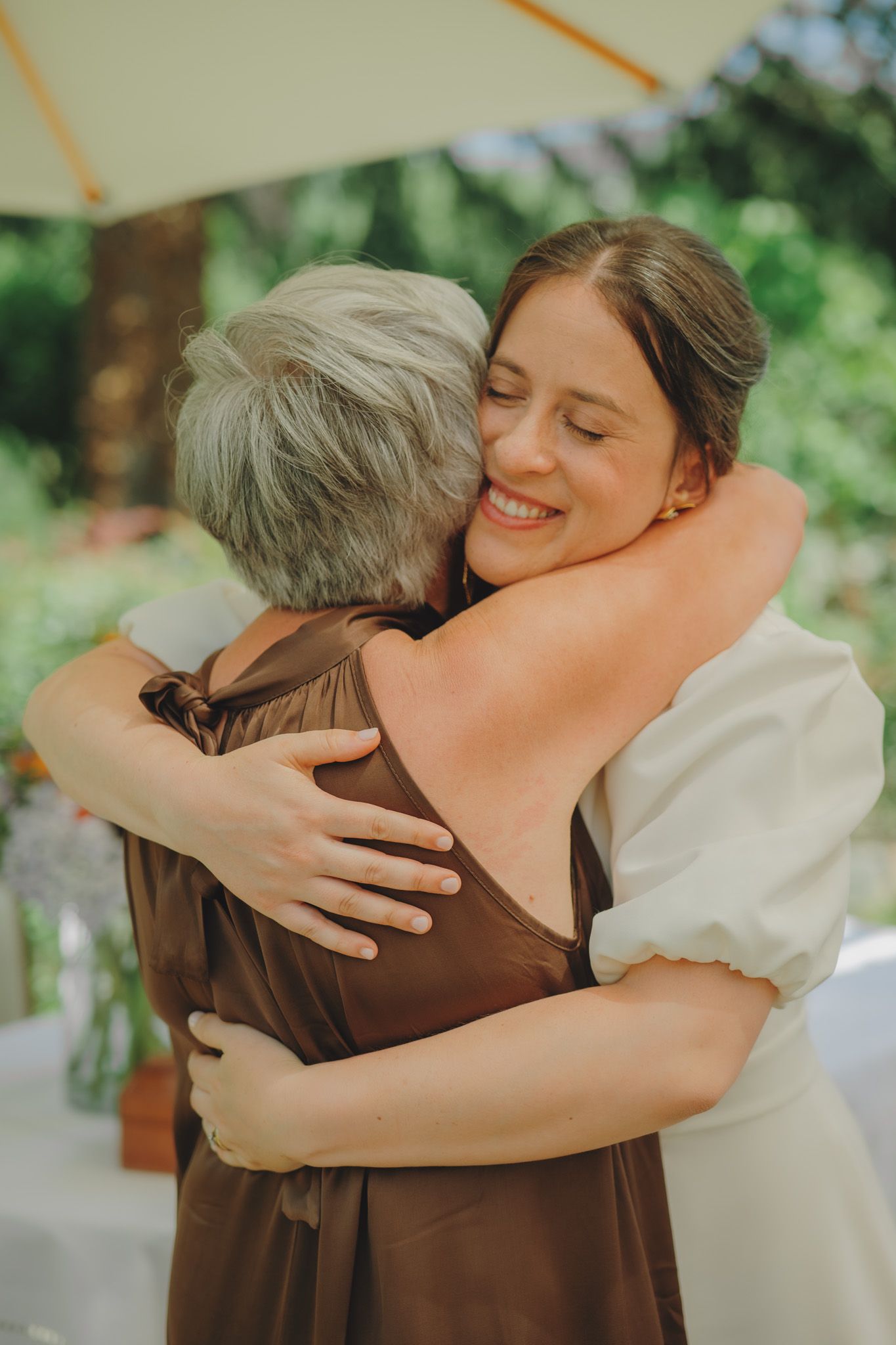 Emotional embrace shared between two people at outdoor celebration.