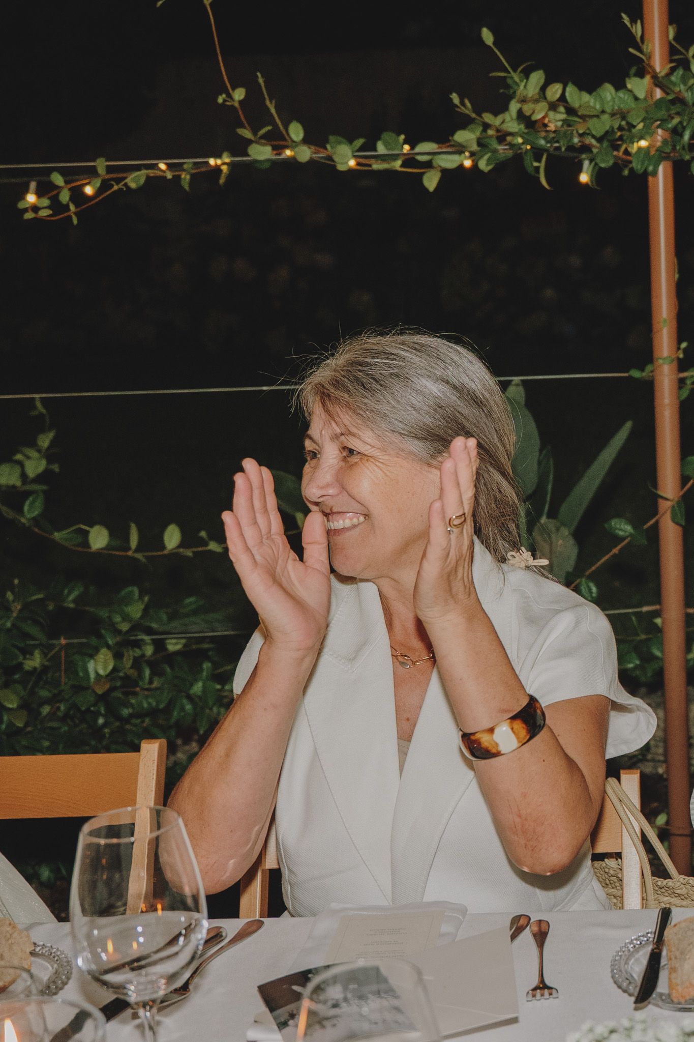 Guest at outdoor dinner party reacting with joy and surprise.