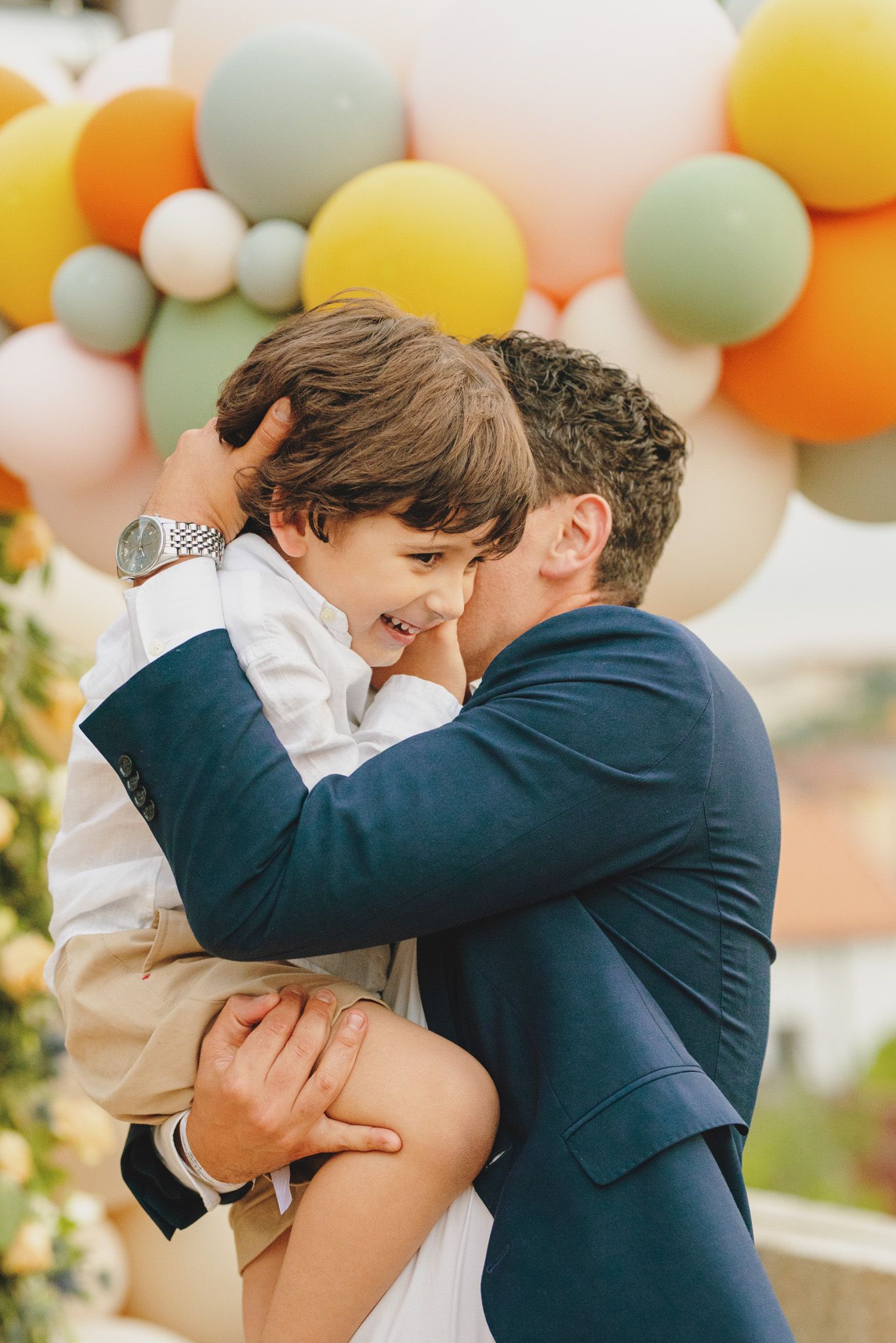 Candid moments of affection captured against a festive balloon backdrop.