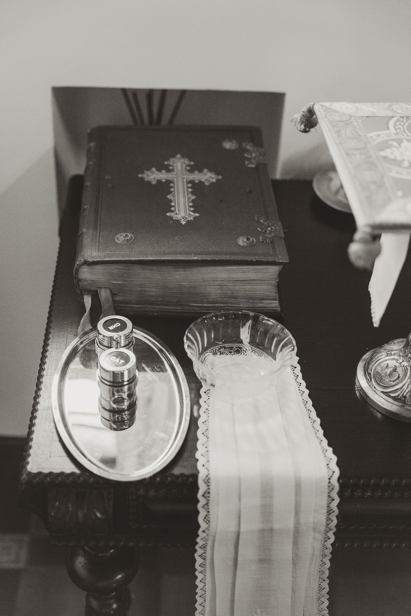 Religious ceremonial items including a cross-adorned book and white linens on a dark surface.