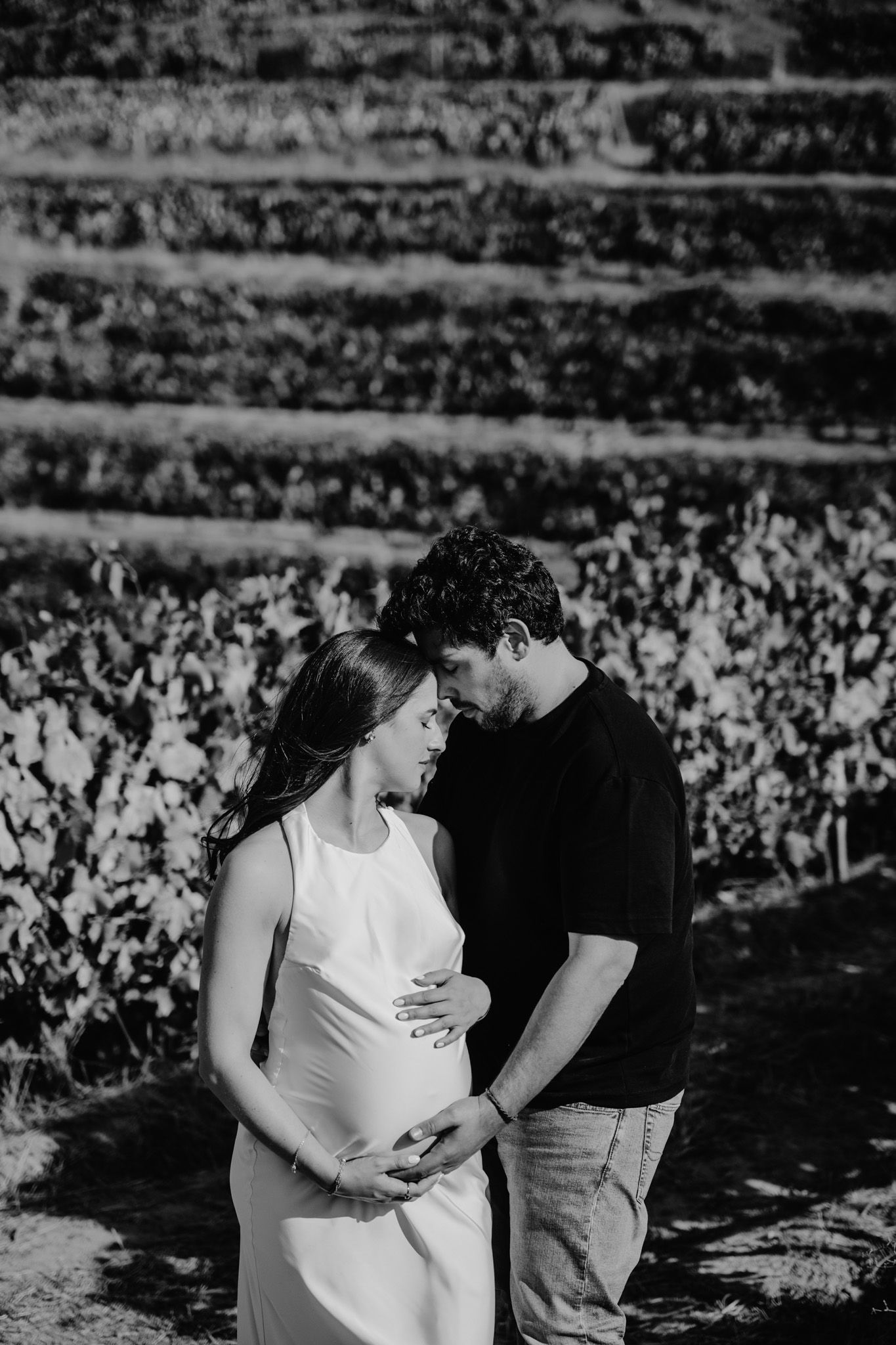 Black and white romantic photoshoot in a vineyard with dramatic lighting and shadows.