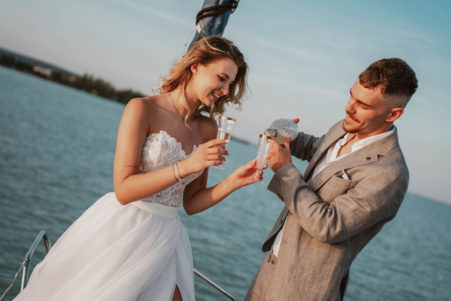 A bride and groom on a sailboat releasing a white dove during their wedding ceremony by the water.
