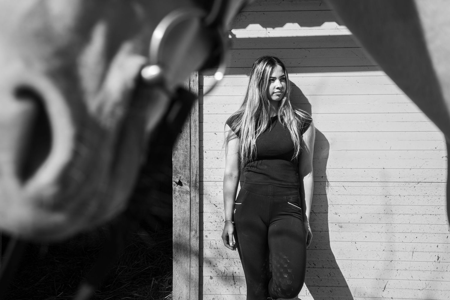 Black and white photo showing a person leaning against a wall outside wearing athletic workout clothing.