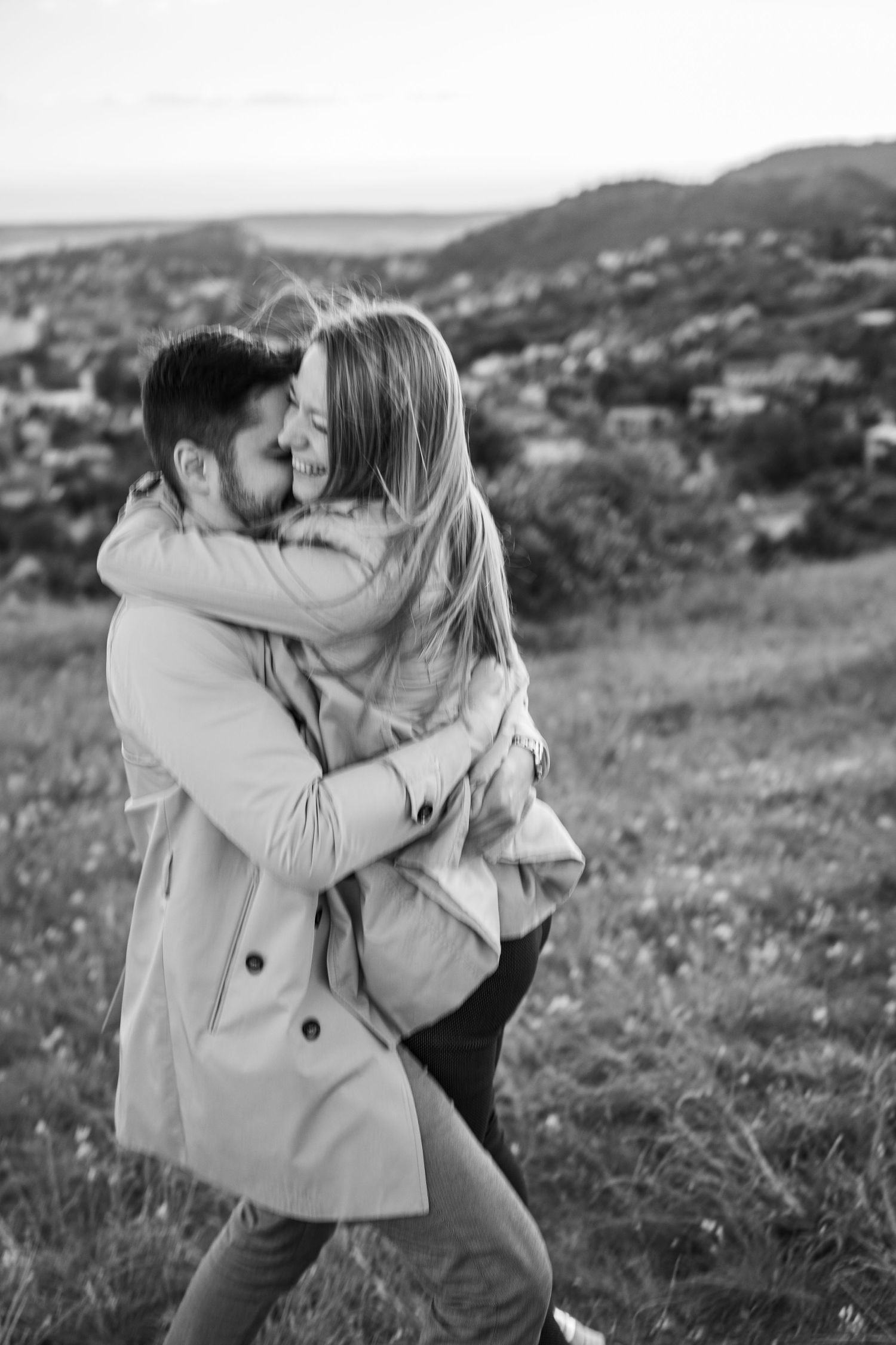 A romantic black and white moment captured on a hilltop with rolling landscape in the background.