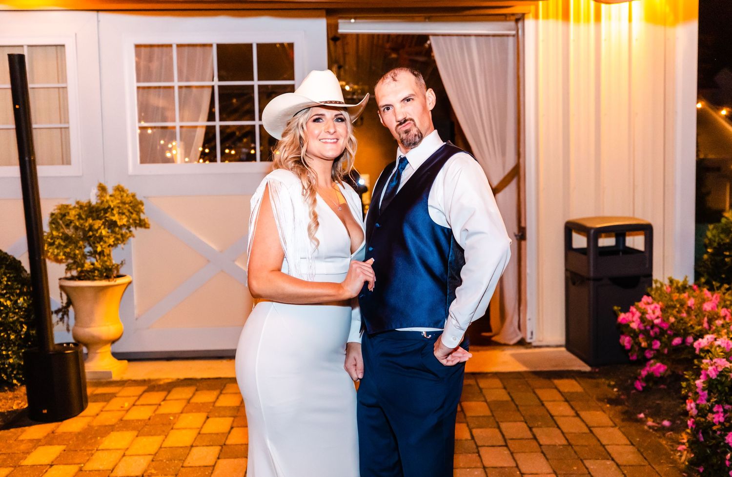 Elegant wedding portrait in front of rustic house with autumn decorations.