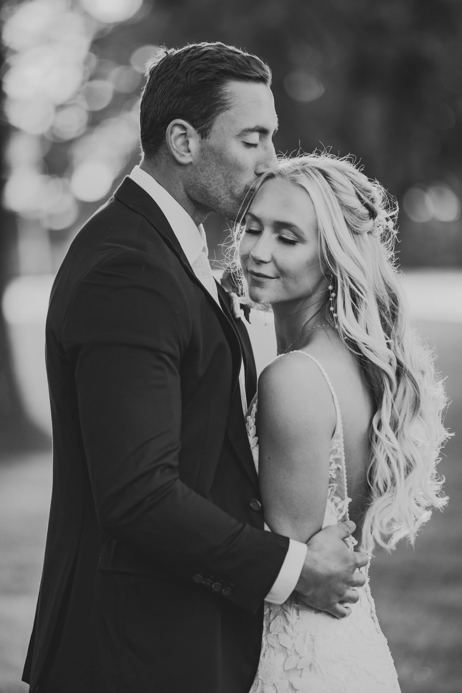 Intimate black and white wedding portrait capturing a tender romantic moment outdoors.