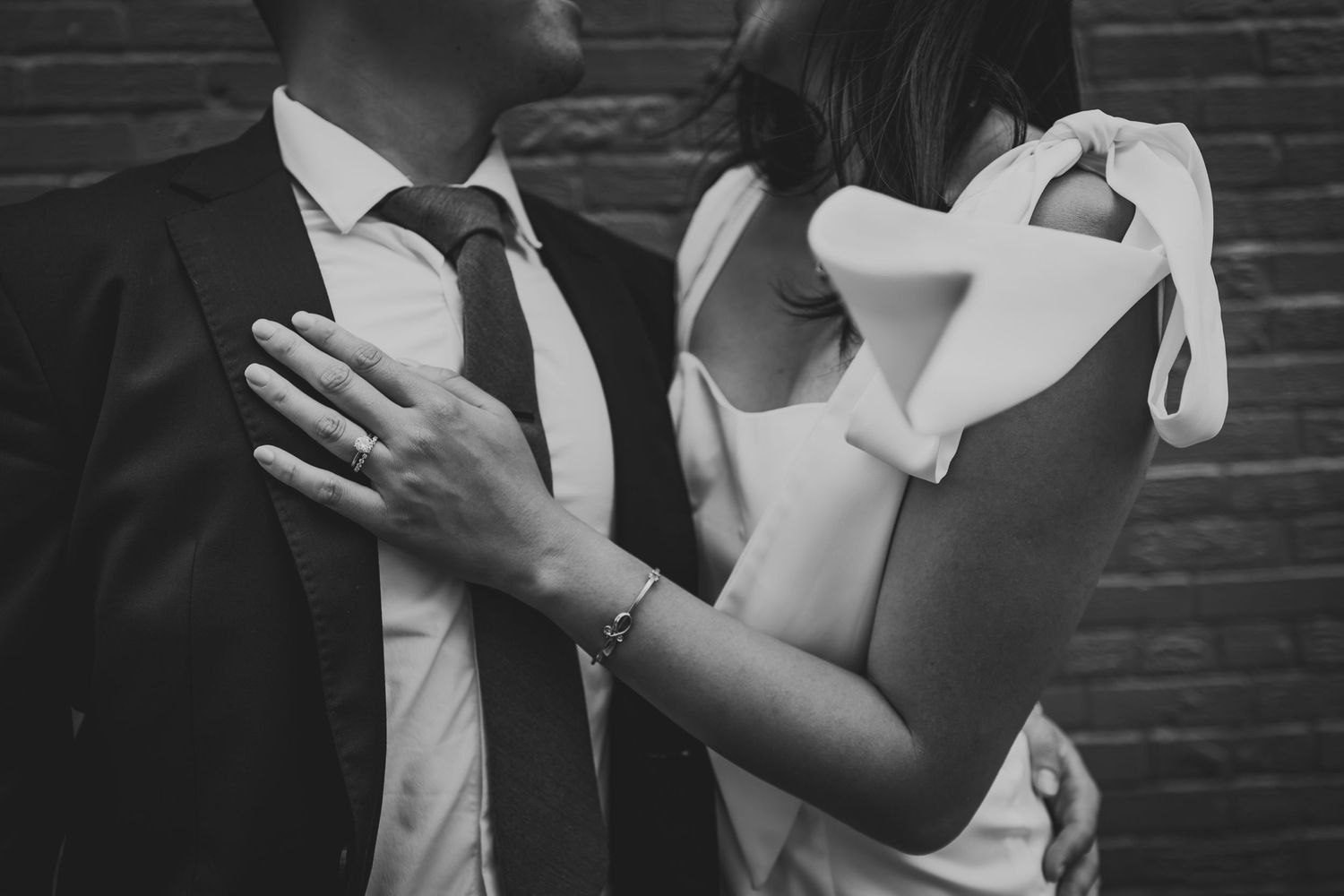 Black and white close-up of formal attire showing elegant dress details and suit.