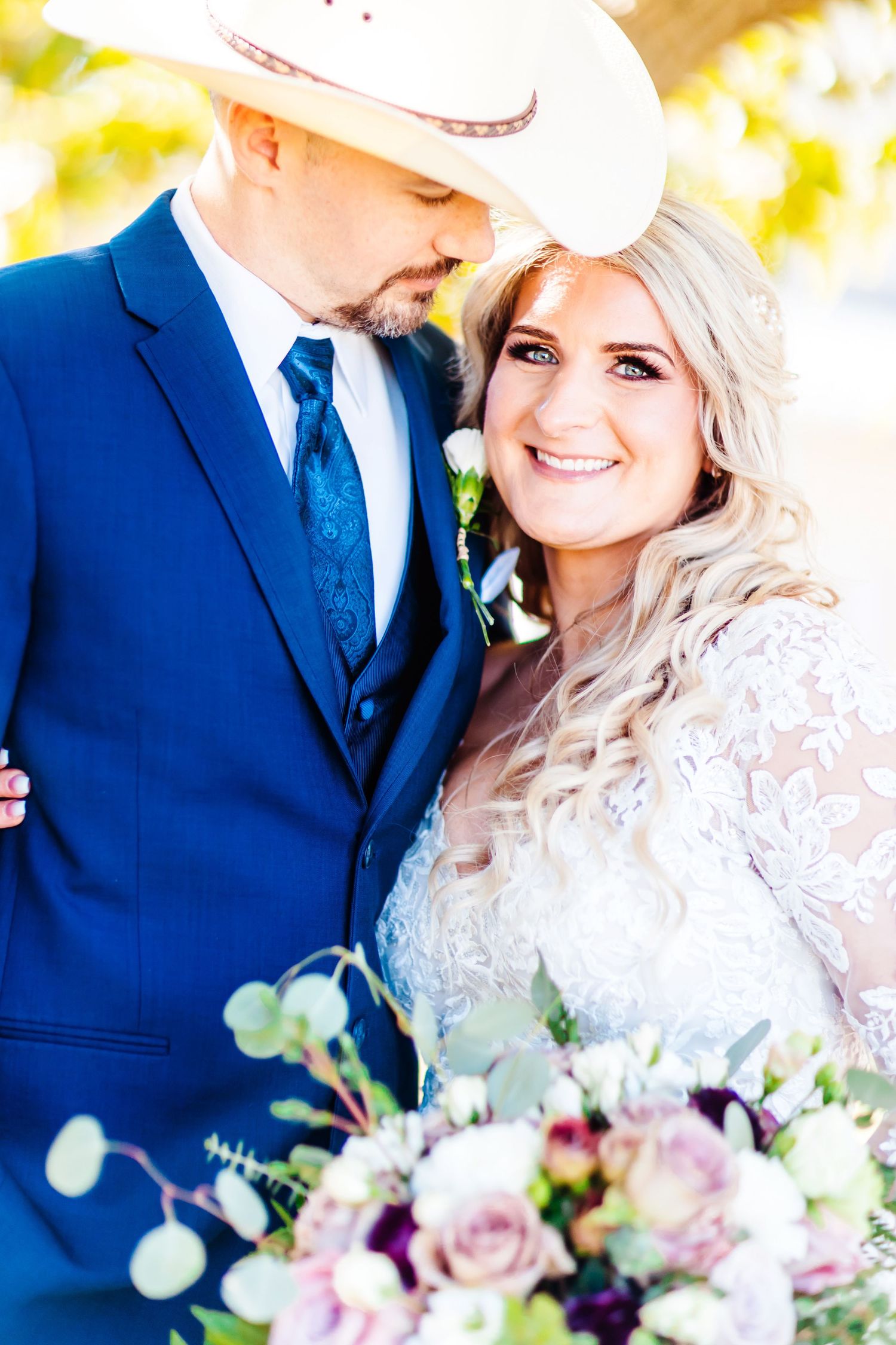 Western-themed wedding portrait with cowboy hat and blue tuxedo.
