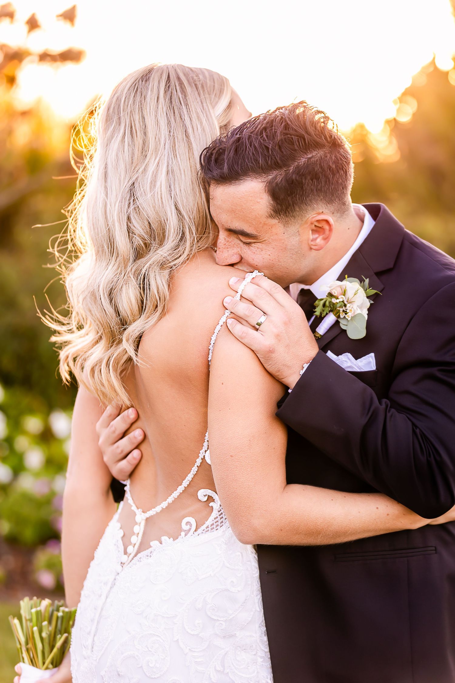 Newlyweds share an intimate moment at sunset with the bride wearing a detailed lace back wedding dress.