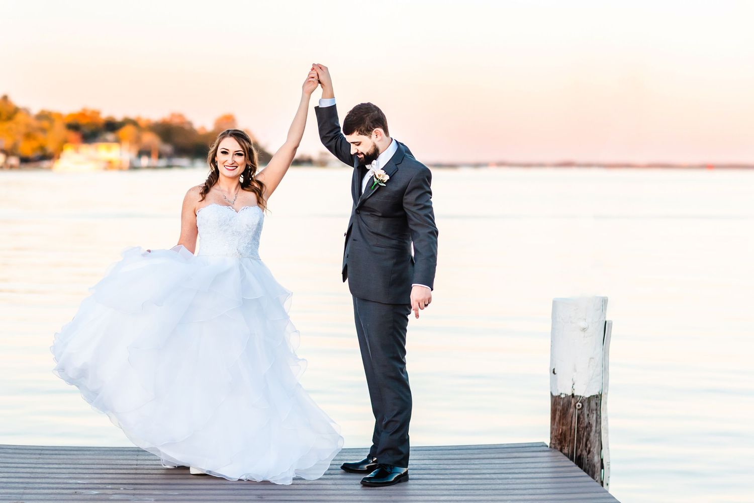 Newlyweds sharing a romantic moment on a wooden pier at sunset.
