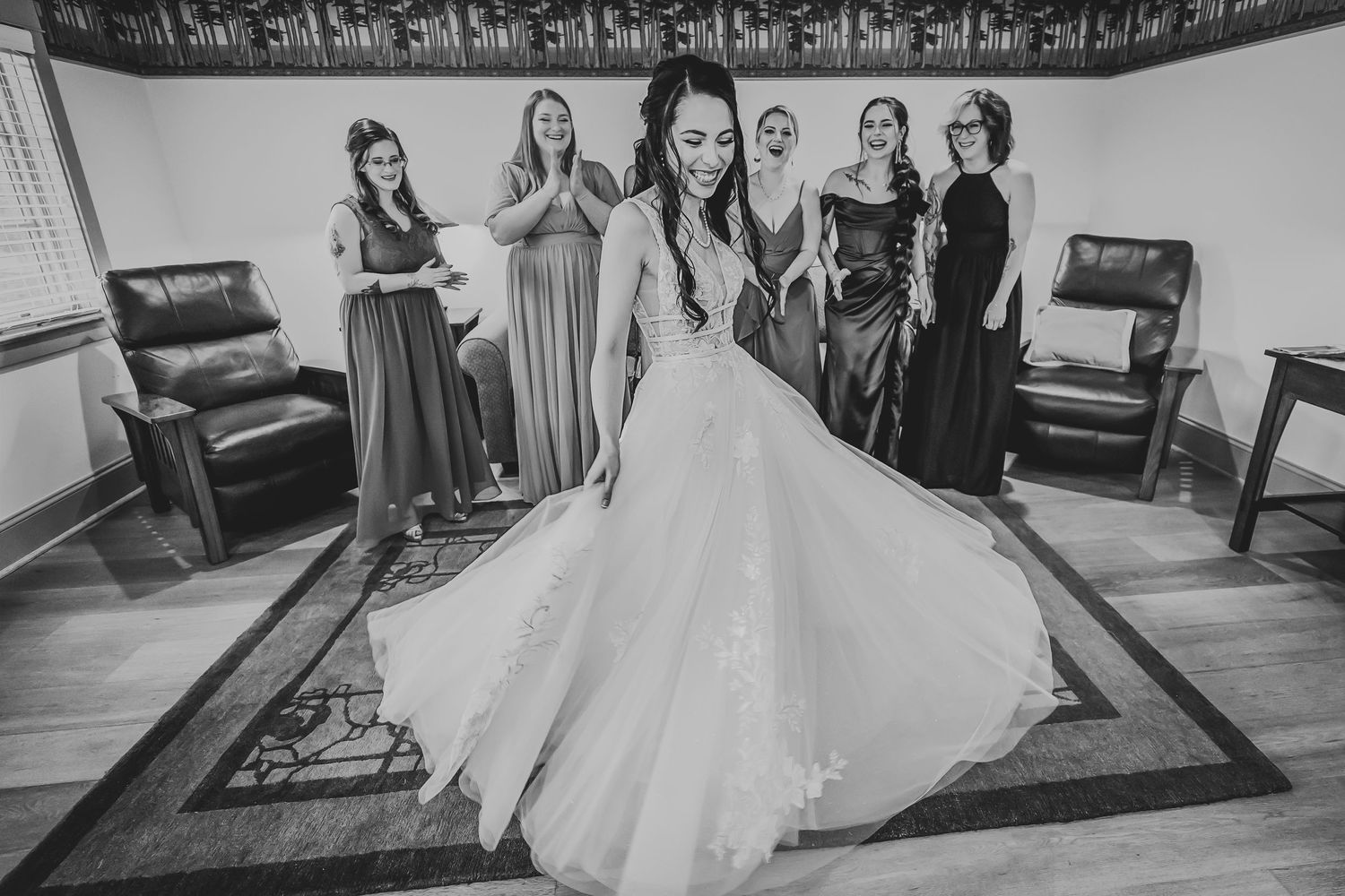 Black and white photo of wedding preparation with bride and bridesmaids in elegant dresses.