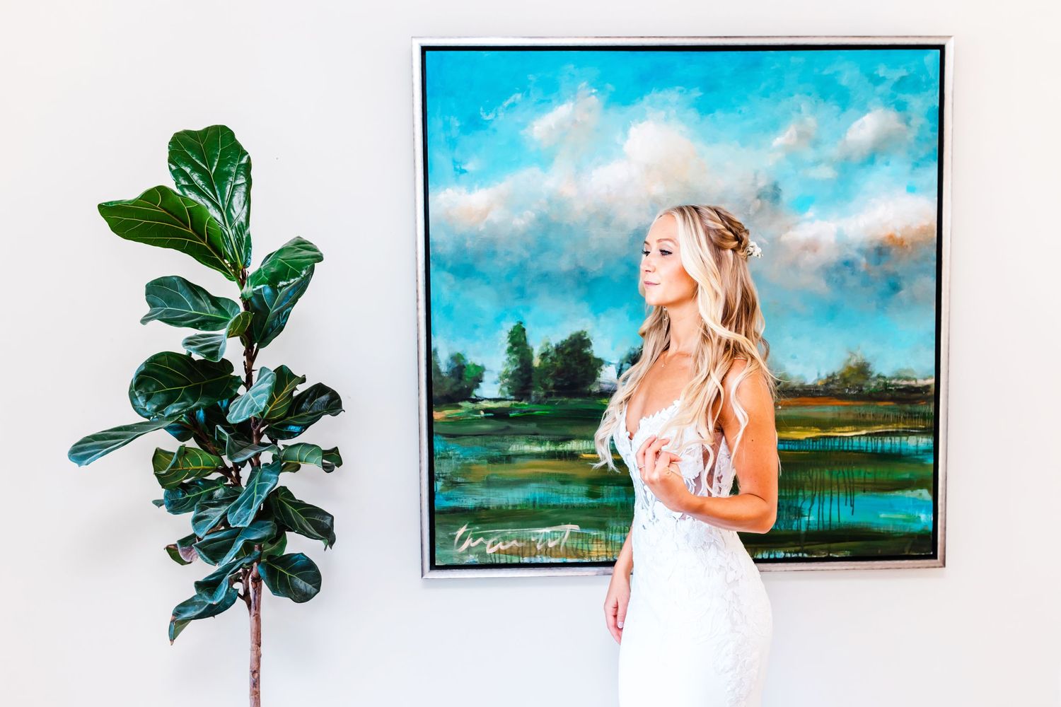 White gown against modern artwork and fiddle leaf fig plant in elegant interior setting.
