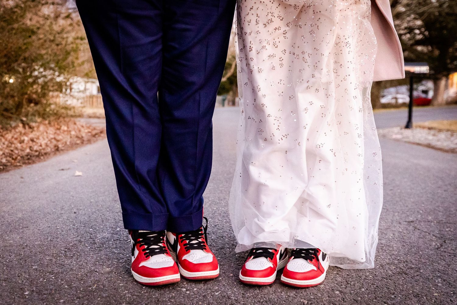 Fun wedding photo showing couple's matching red and white sneakers under formal attire.
