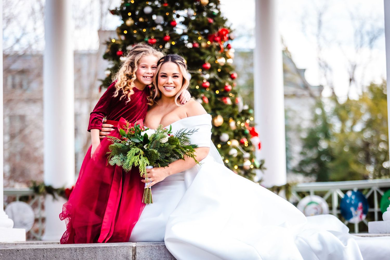 Holiday wedding scene with Christmas tree and red and white decor in gazebo setting.