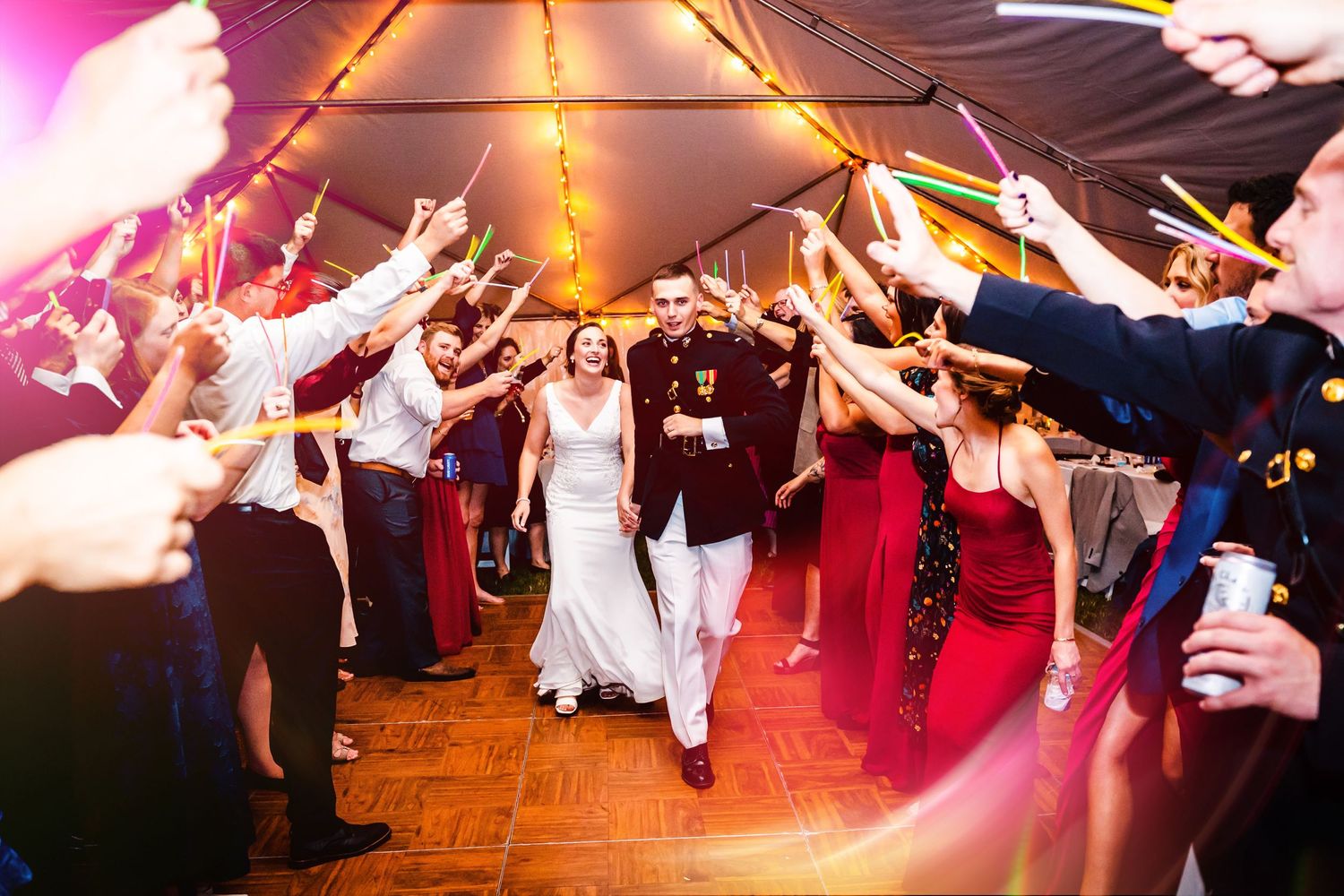 Lively wedding reception exit with guests forming a tunnel of sparklers.