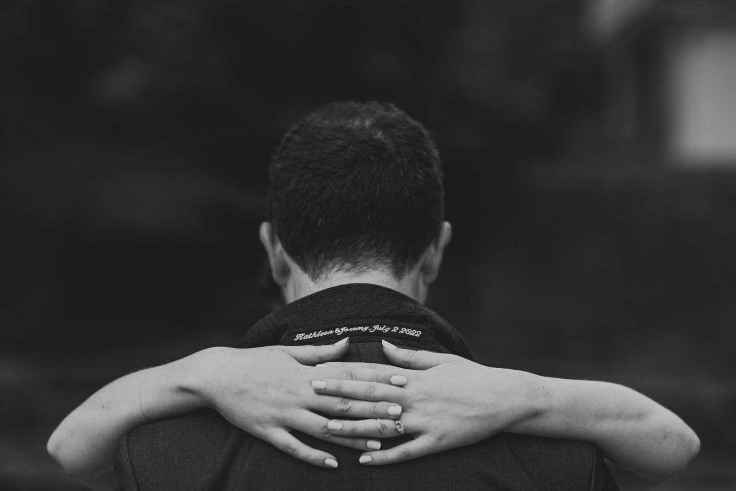 Artistic black and white photo showing hands clasped behind someone's neck.