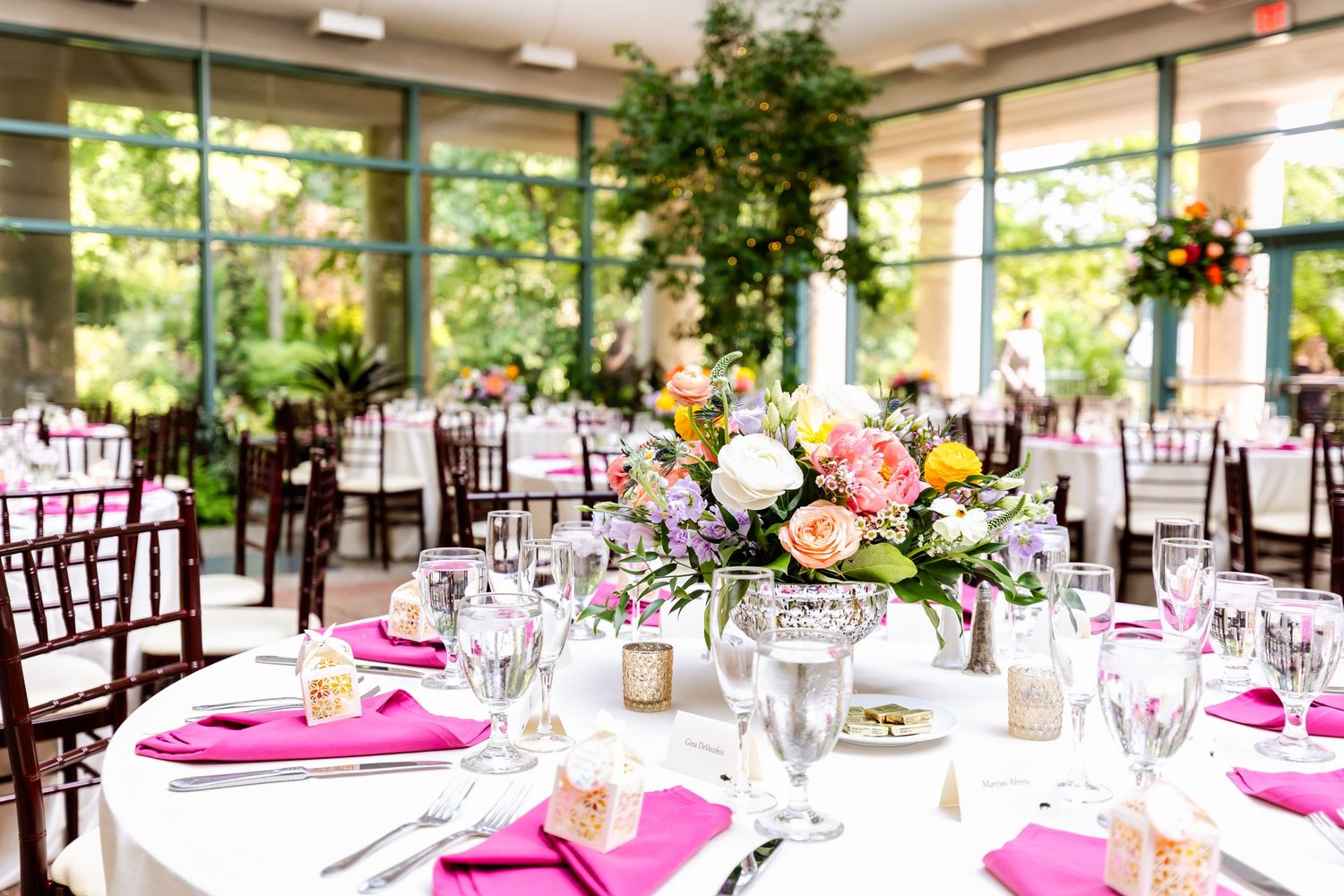 An elegant wedding reception setup with pink accents and floral centerpieces.