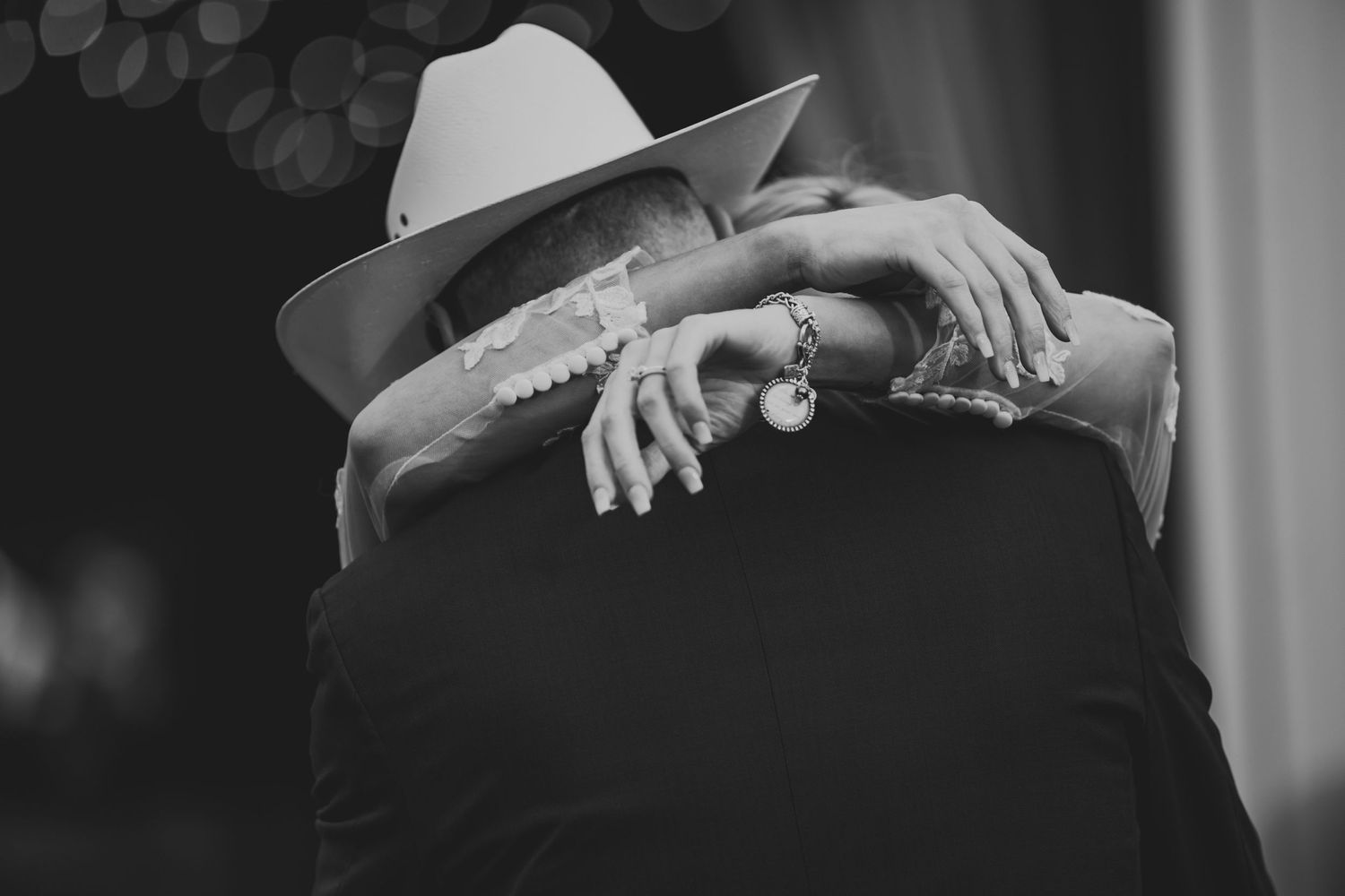 Intimate black and white portrait showing wedding rings and western hat.