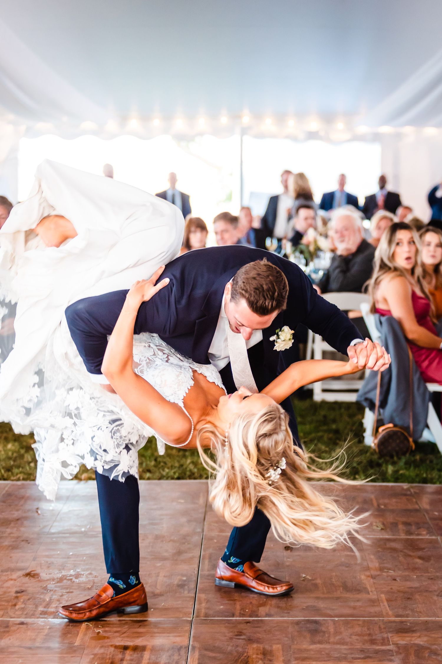 Dramatic dip during first dance at wedding reception under white tent.